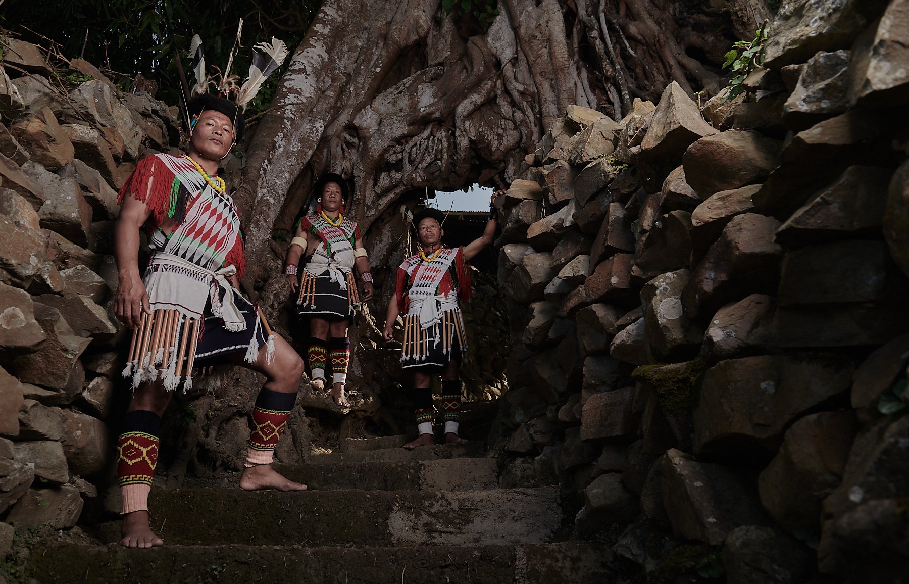 3 warriors from the Angami tribe standing under a tree gate, Tuophema village, Nagaland