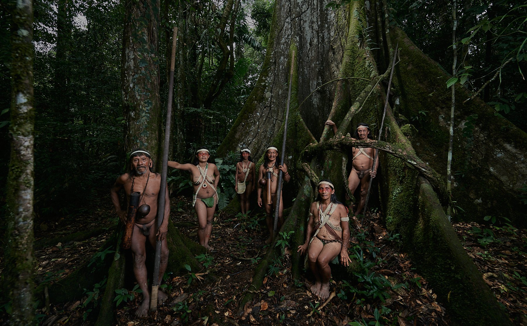 Warriors and women of the Huaorani tribe next to one of the giant trees in the jungle