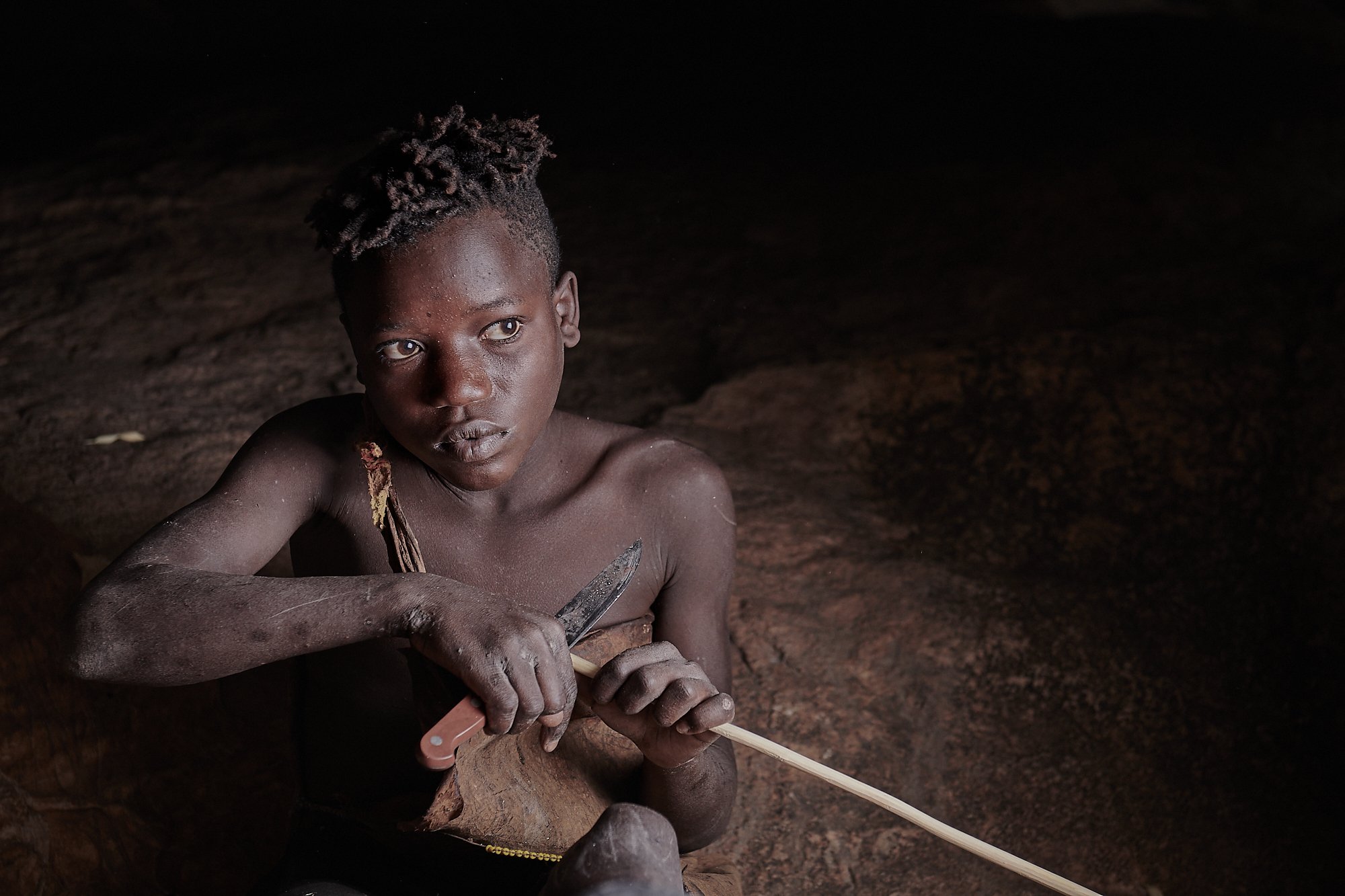 Young Hadzabe boy perfecting his arrow-making