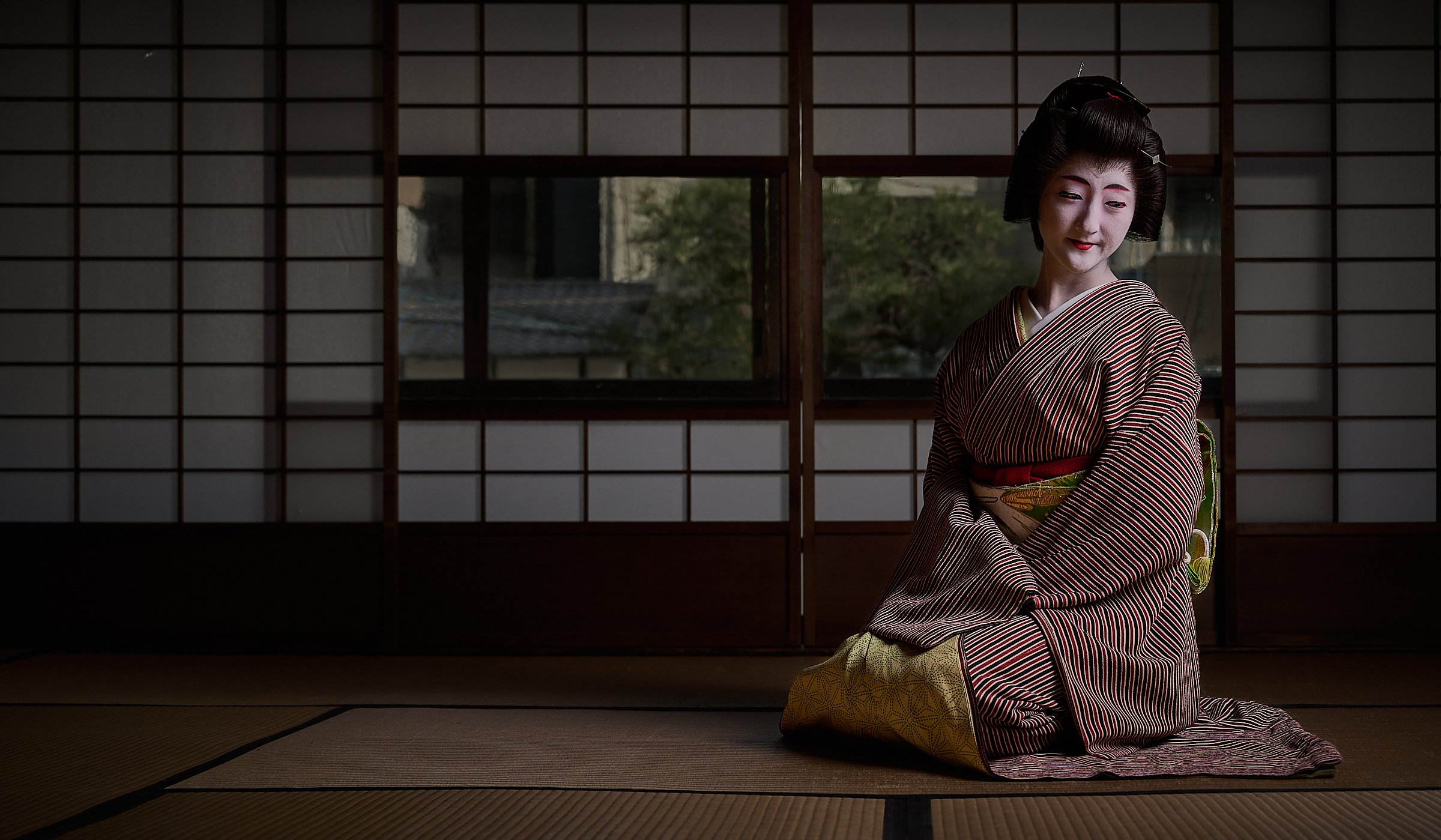 Masaki displaying the elaborate way in which geishas sit, here before a garden in a 150yr old merchant house