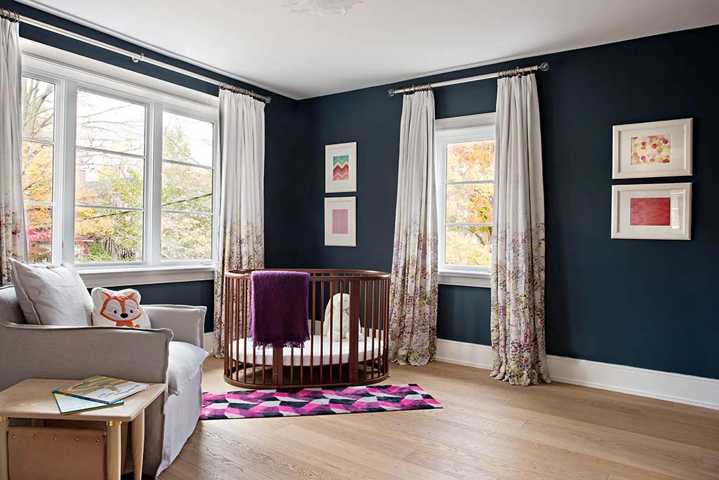 Sweet baby room with round crib and deep teal wall paint designed by Four Blocks South, residential interior design located in Toronto, Canada.
