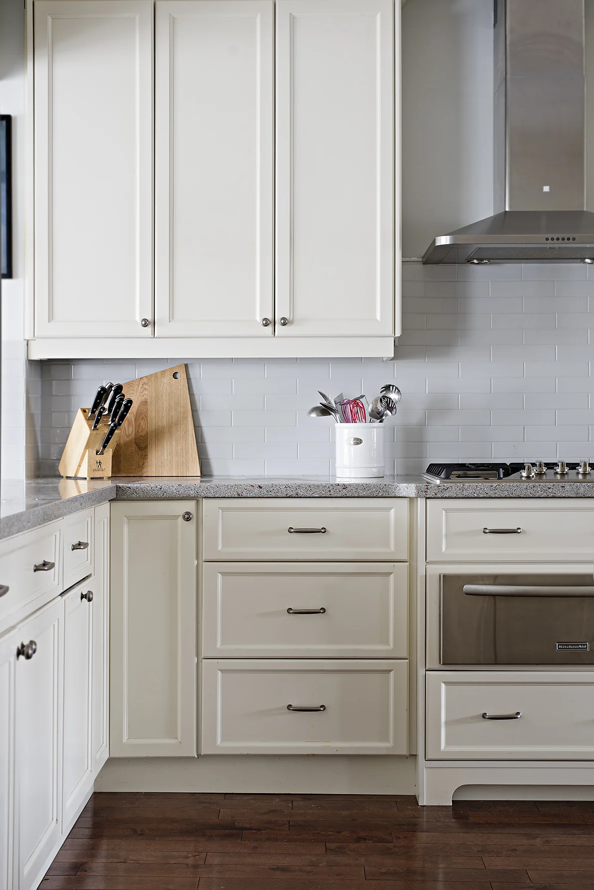 Kitchen with wood flooring, white cabinets and tiled backsplash