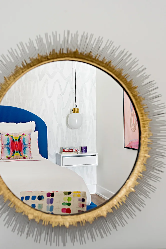 A brass statement mirror reflects the modern details in this urban bedroom design.