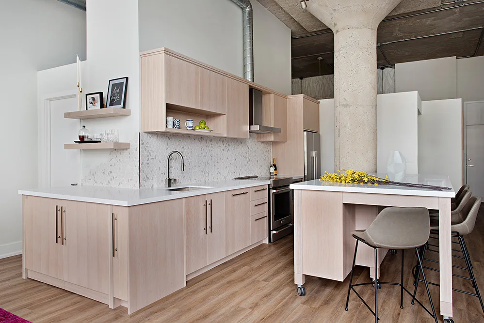 Hidden laundry machines at the end of the kitchen and moveable island function as a bar areas for parties in this white oak loft kitchen.