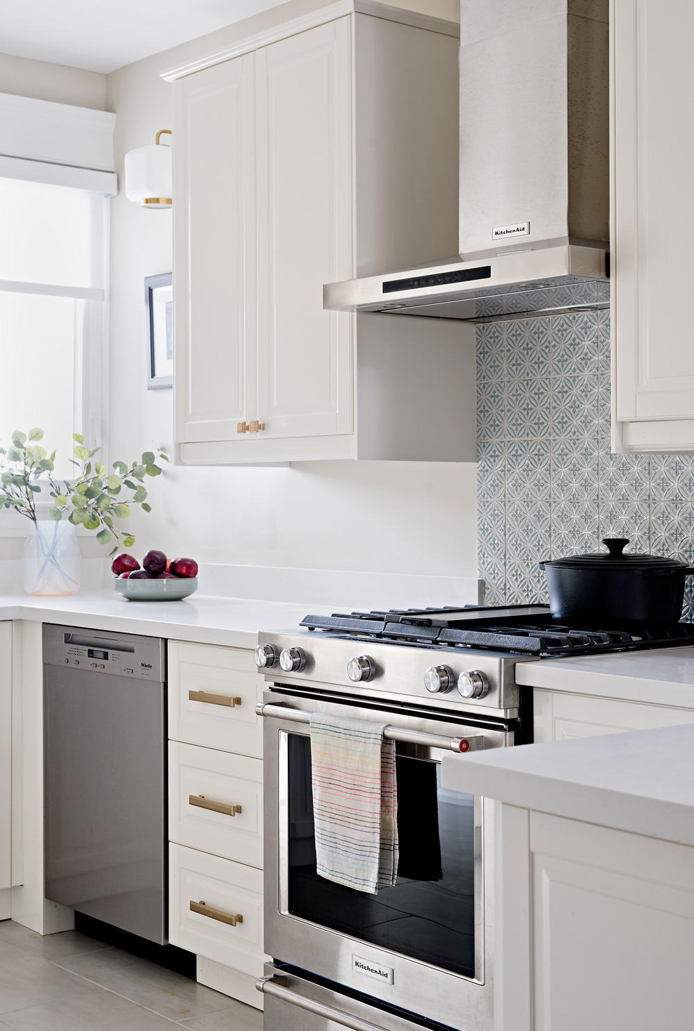 Stainless steel KitchenAid appliances in stunning white Ikea kitchen with brass accents.