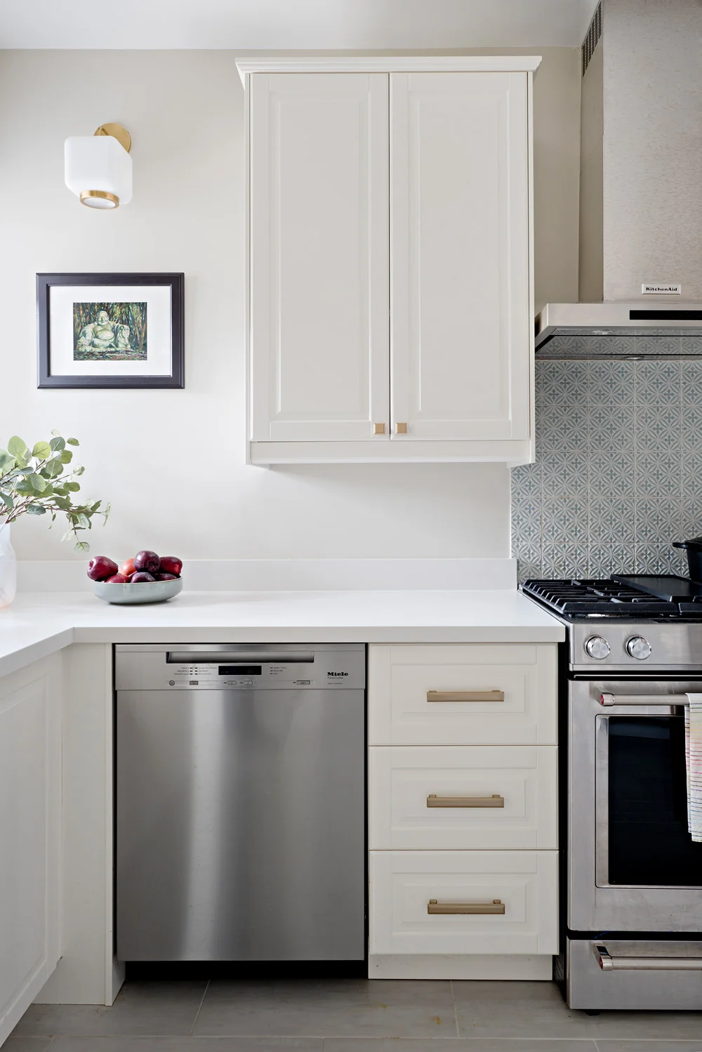 Stainless steel appliances and brass accents, mixed metals in a creamy white kitchen.