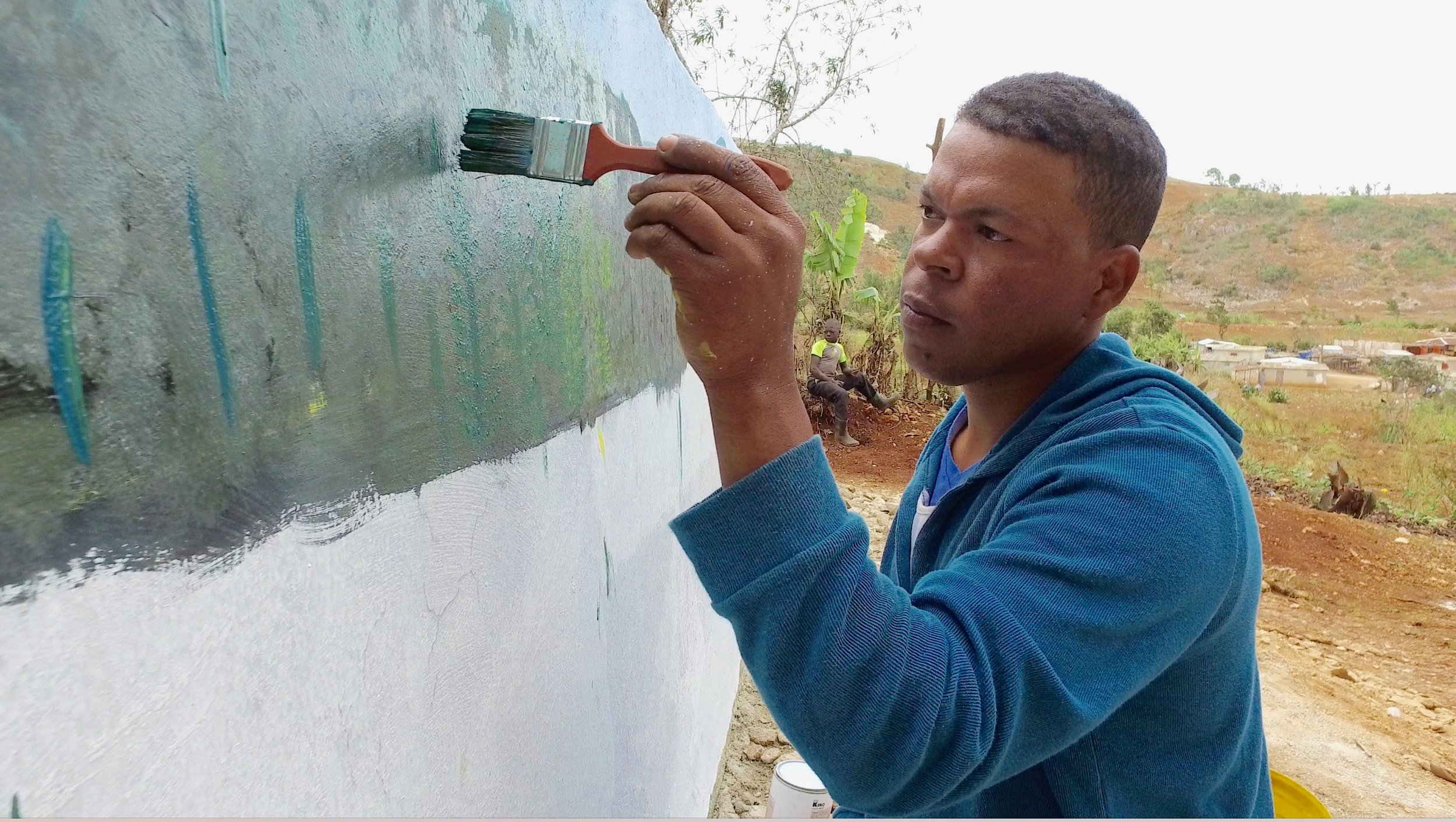 Former Poacher turned field biologist painting a mural about the Diablotin on the new drinking water cisterns.