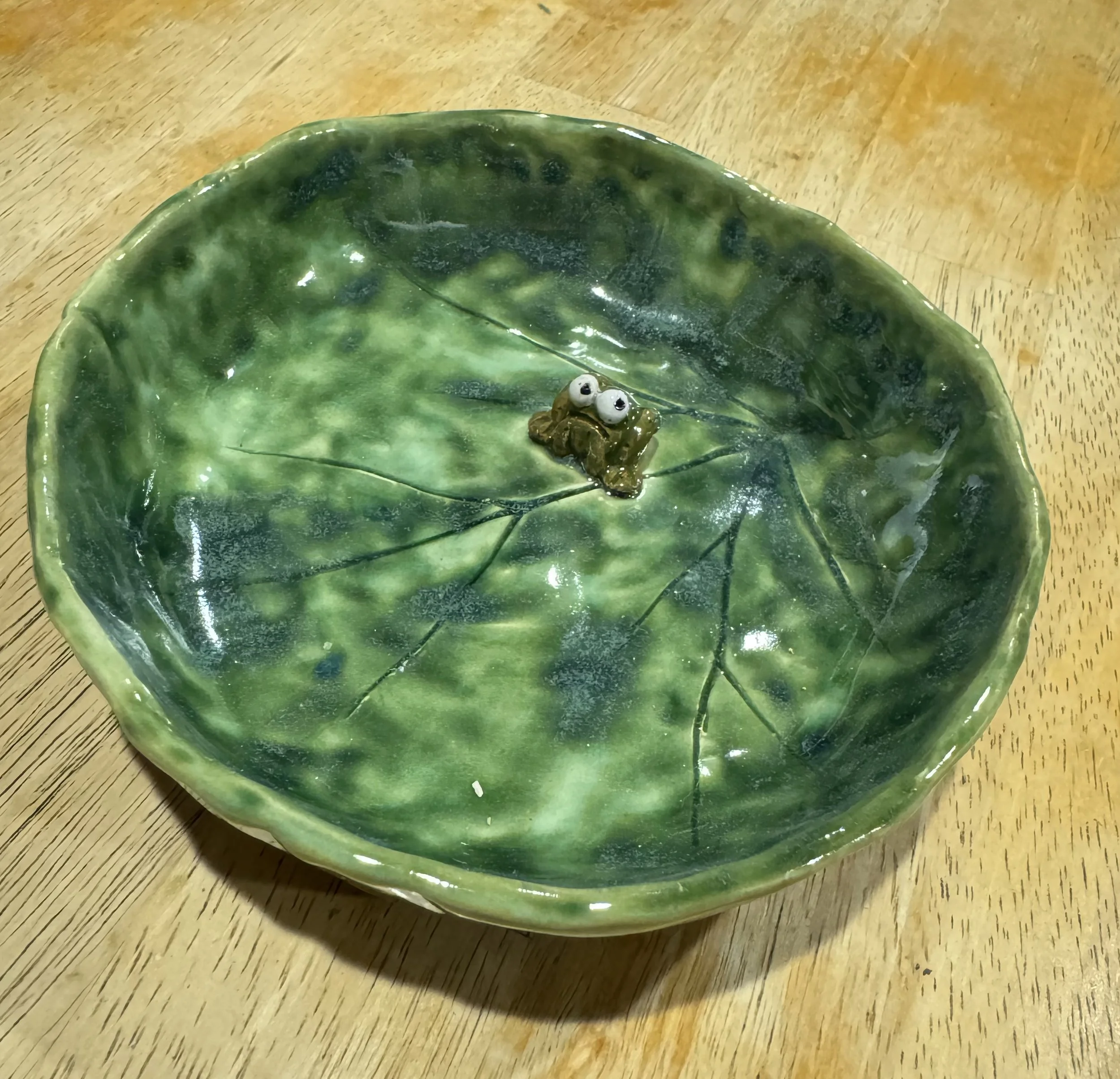   Kathy Ho    LEAF ME ALONE! , 2026  Ceramics   Description:  Frogs are sometimes found on vegetation - and some are much smaller than the leaves they are found on 