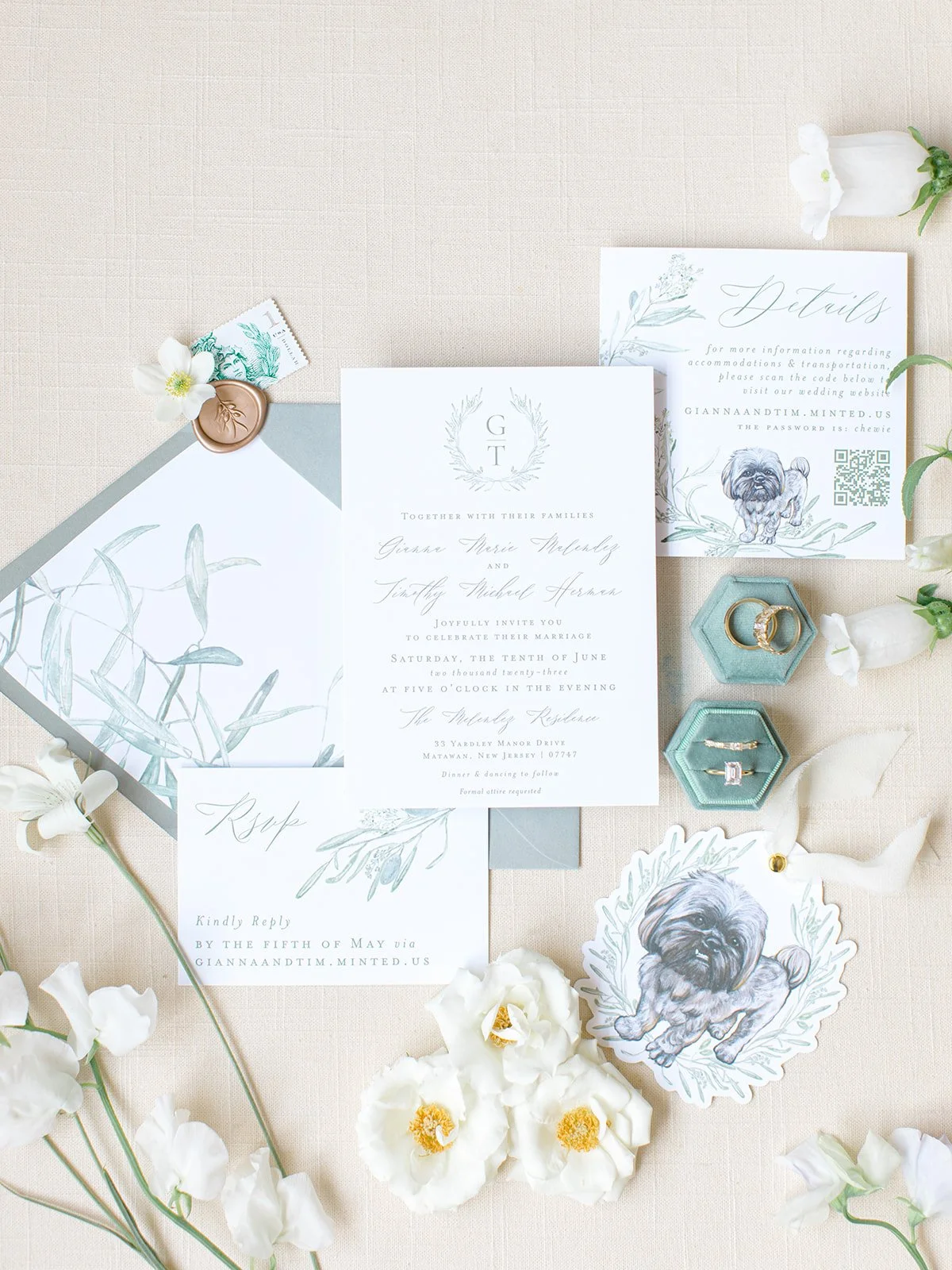 Wedding invitation suite with floral accents, a dog illustration, rings in hexagonal boxes, a RSVP card, and white flowers arranged on a neutral background.
