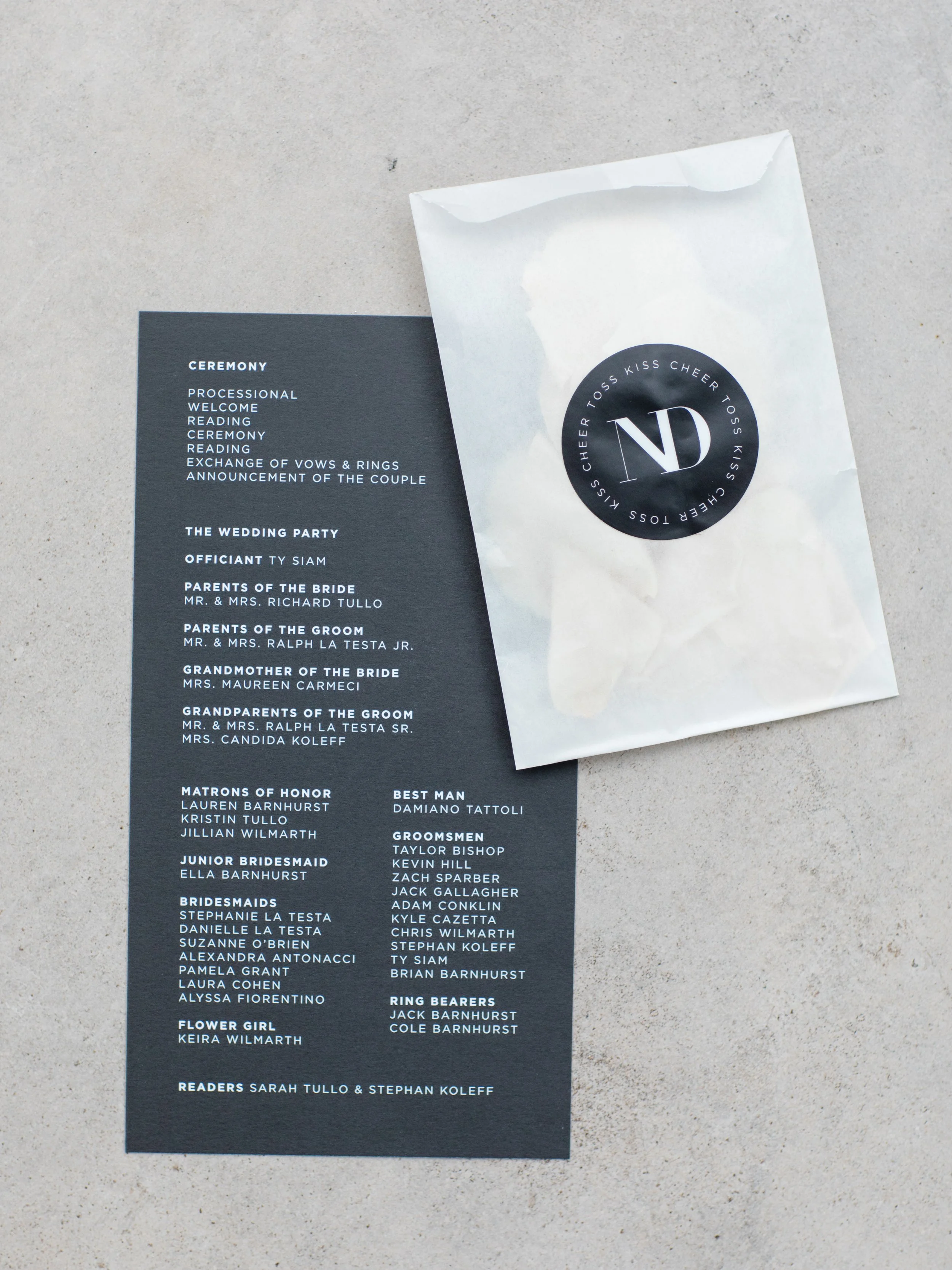 Wedding ceremony programs and a small bag with a black circular sticker that has a white 'ND' logo surrounded by the word 'cheer' repeated in a circle.