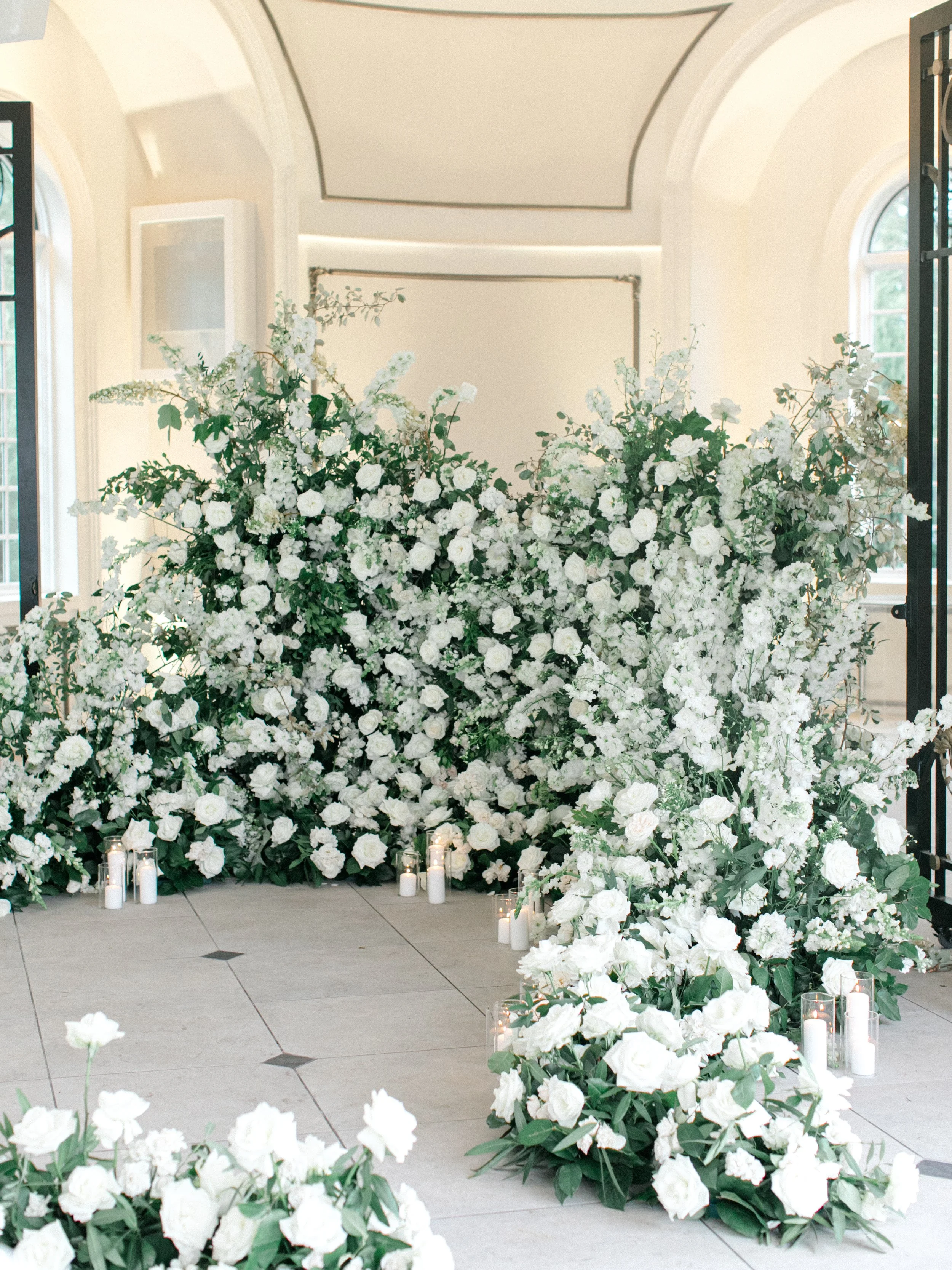 White floral arrangement and candles inside a decorated indoor venue.