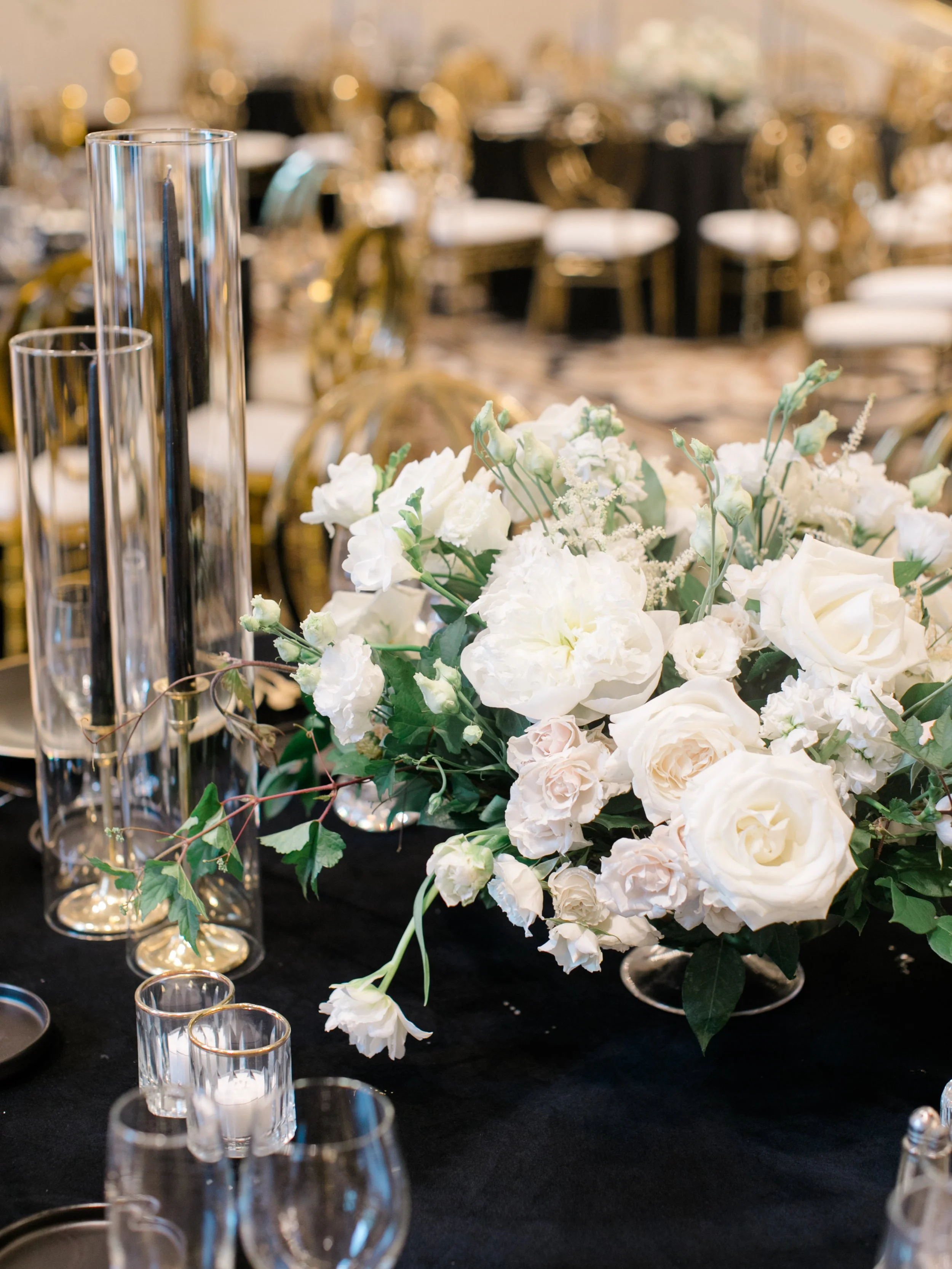Elegant table centerpiece with white flowers and tall glass candle holders at a formal event.