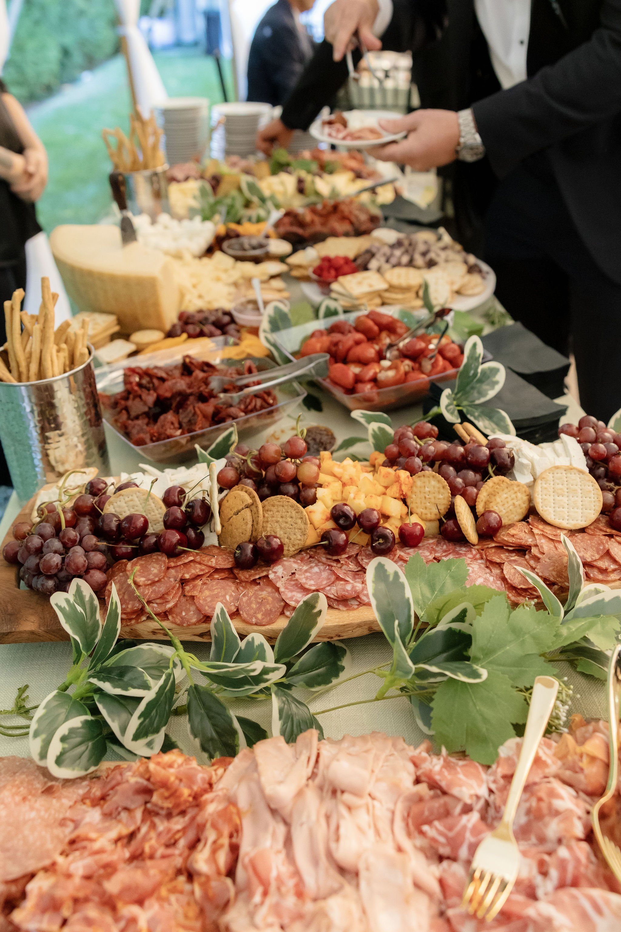 A buffet table with assorted cheeses, meats, fruits, crackers, and appetizers at a gathering.