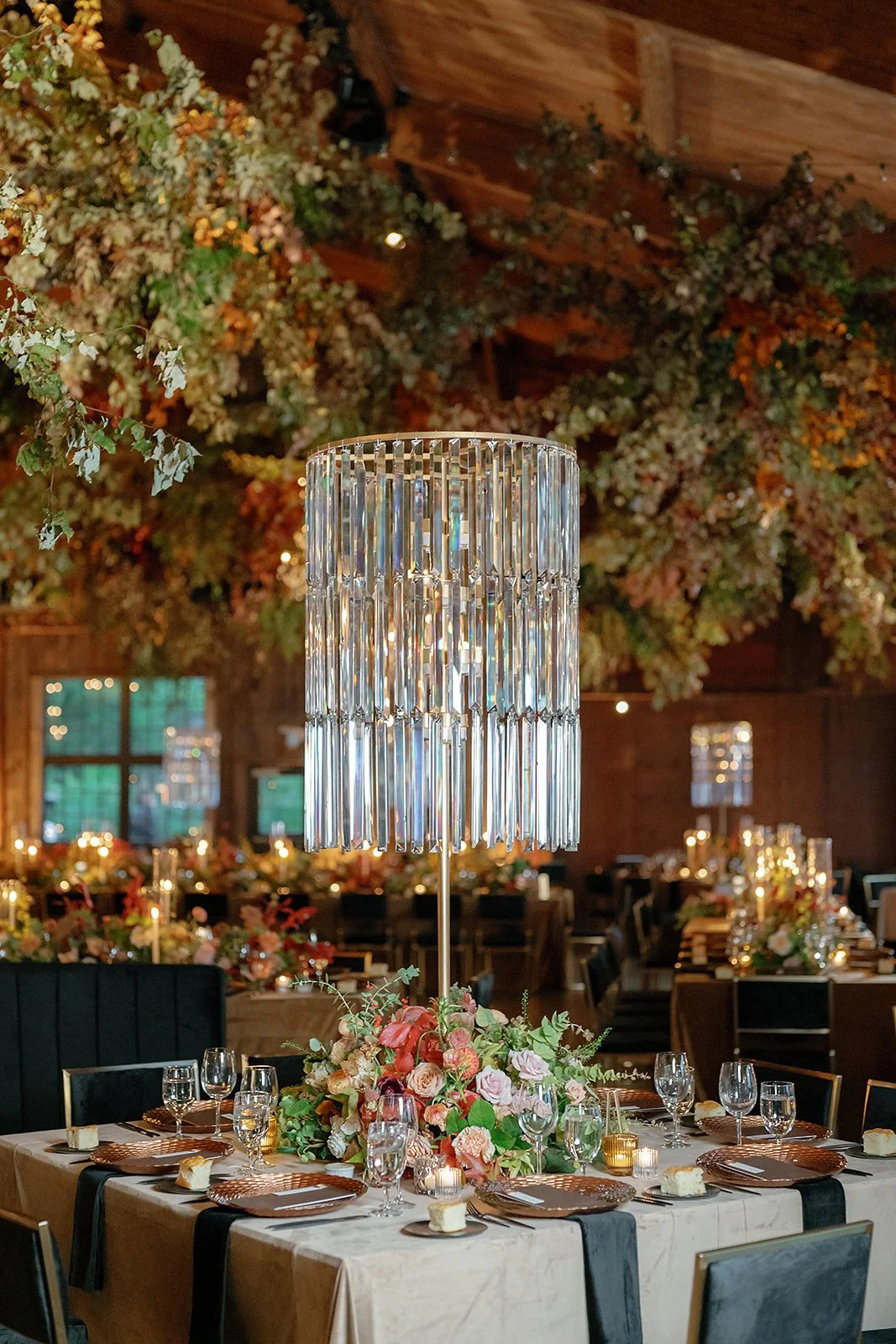 Elegant banquet table with floral centerpiece, crystal chandelier, and ambient lighting in a decorated event space.