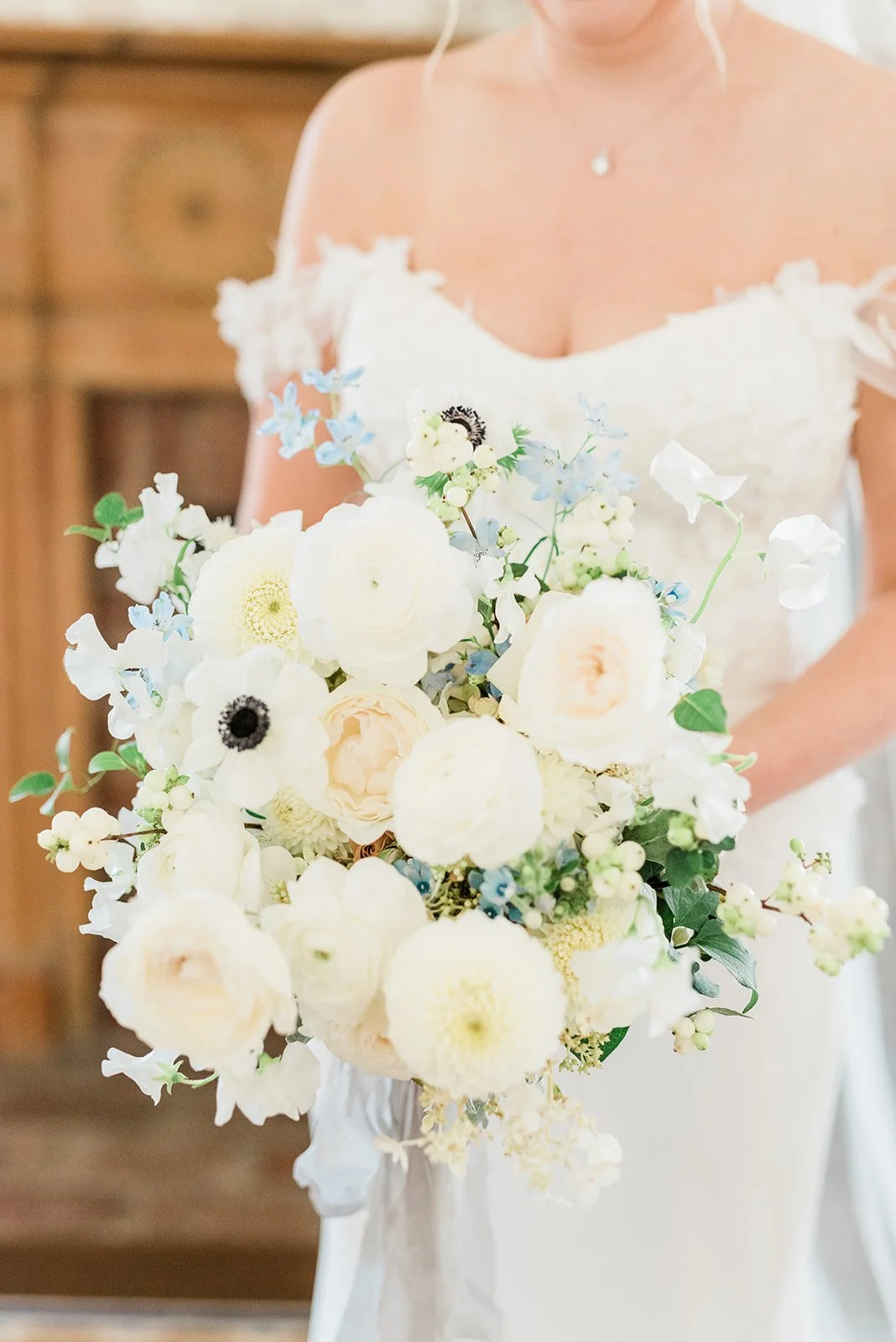 A bride holding a large bouquet of white and pastel flowers.