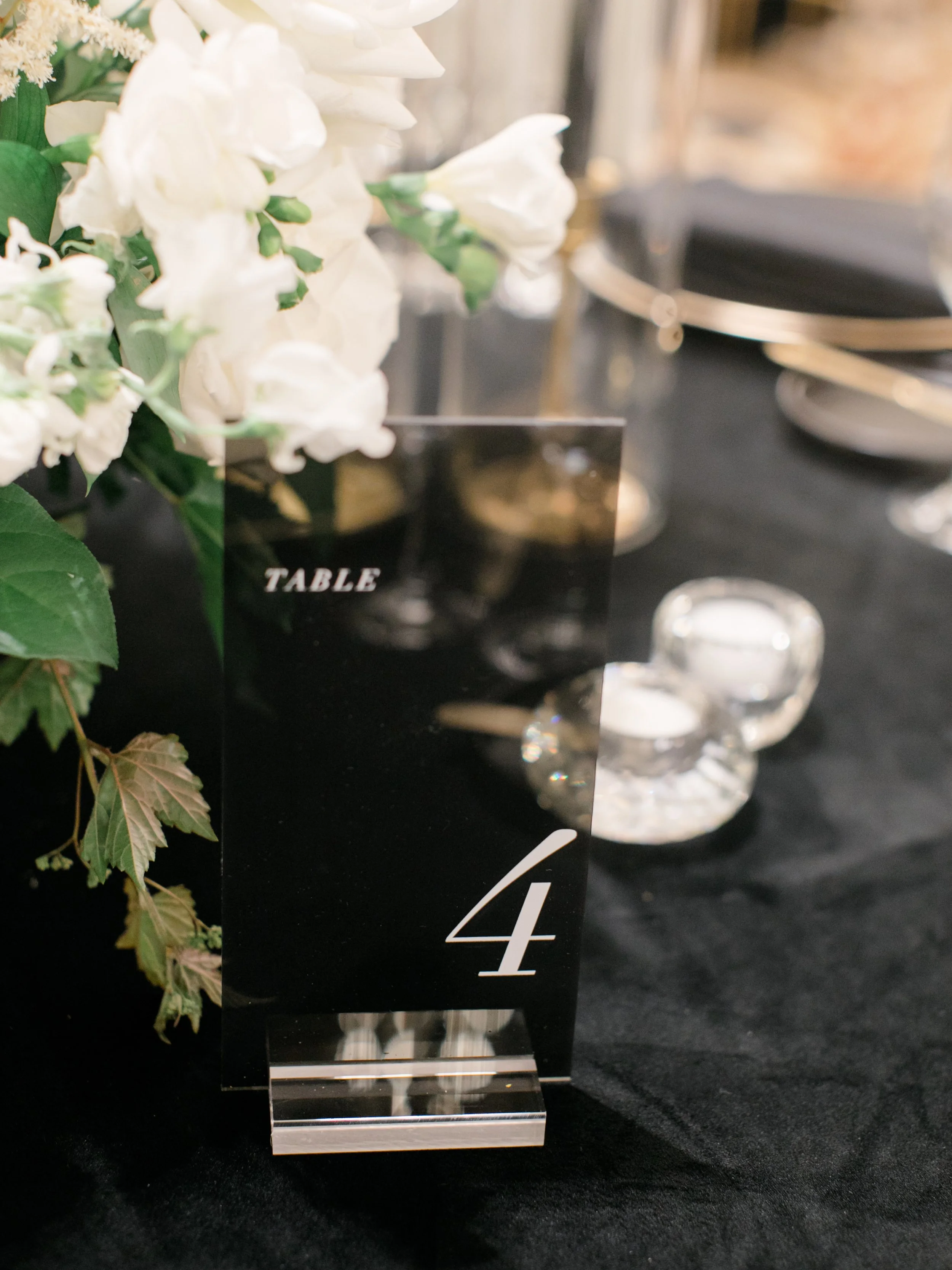 Table number 4 on a black table with white flowers and glassware.