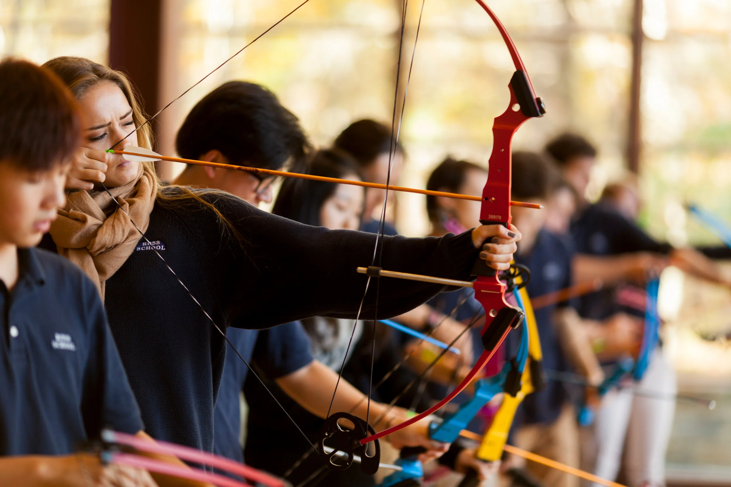 Ross Upper School students engaged in archery lesson.