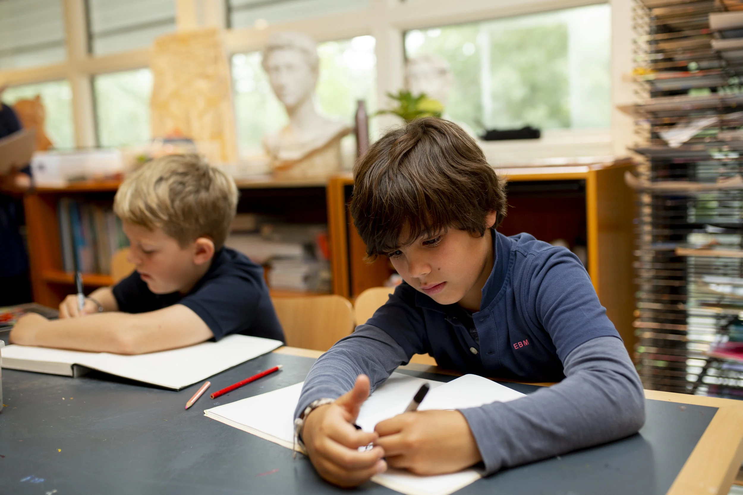 Ross Elementary students at work in art studio with classical bust in background.