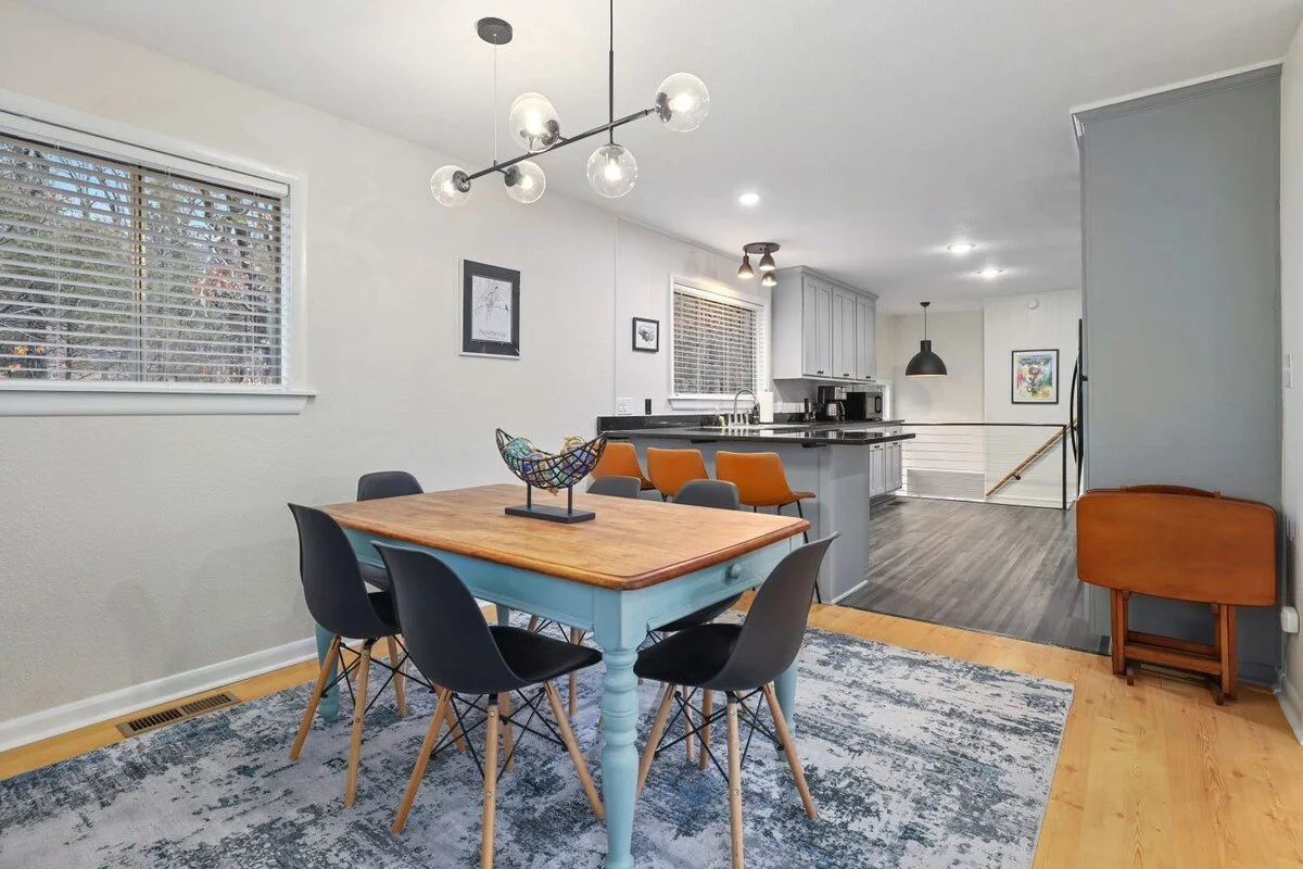 Walk through the living room and you'll find our dining room and kitchen area. To the left, you'll see our six-top dining table as well as a two-top bar area.  To the right, you'll see three leather barstools overlooking the kitchen.