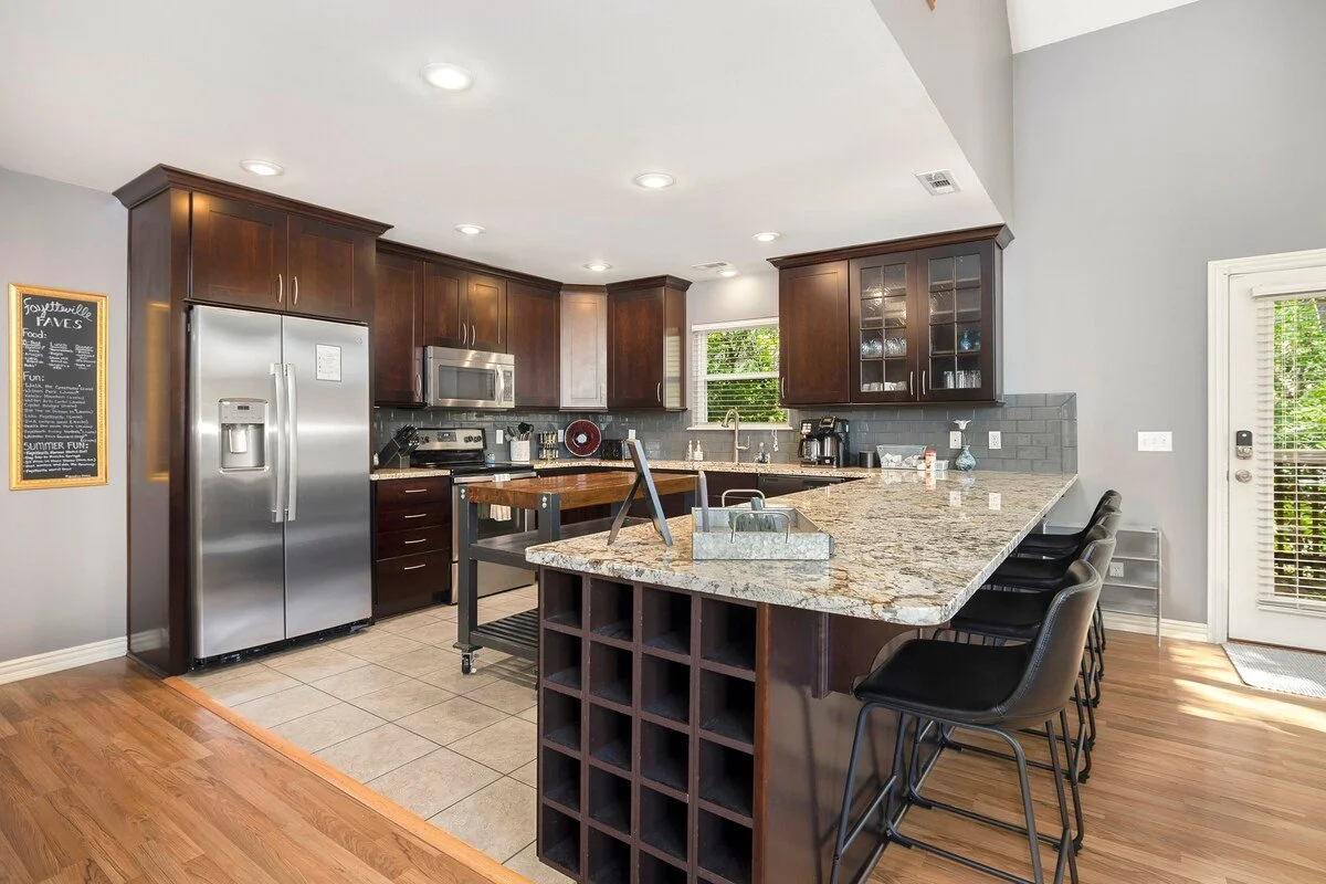 Our kitchen features a wood-top island, high-end amenities and appliances, a built-in wine rack and a large bar with seating.