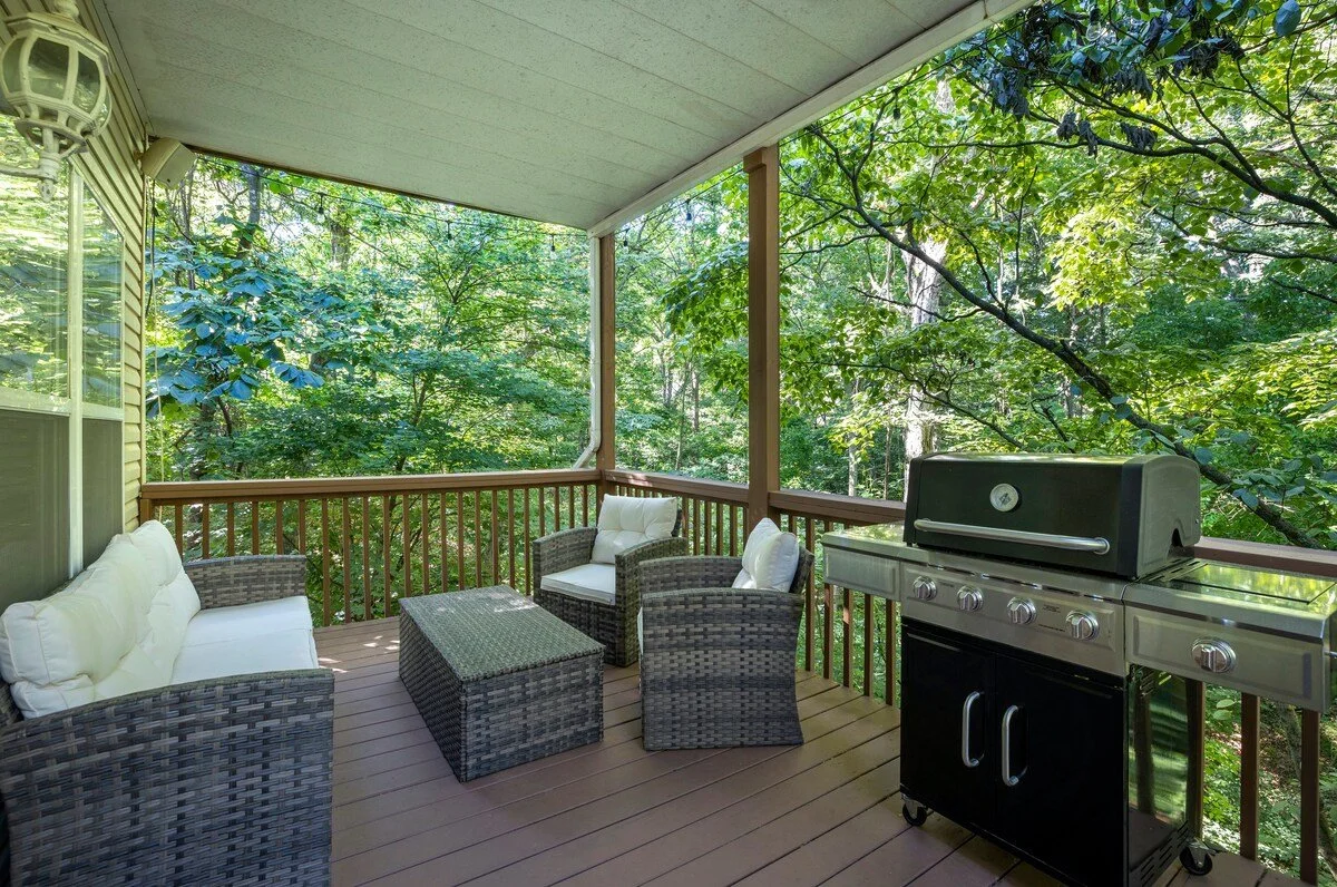 The main level of our home has a wooden deck with a gas grill, a seating area, and an outdoor dining space. 