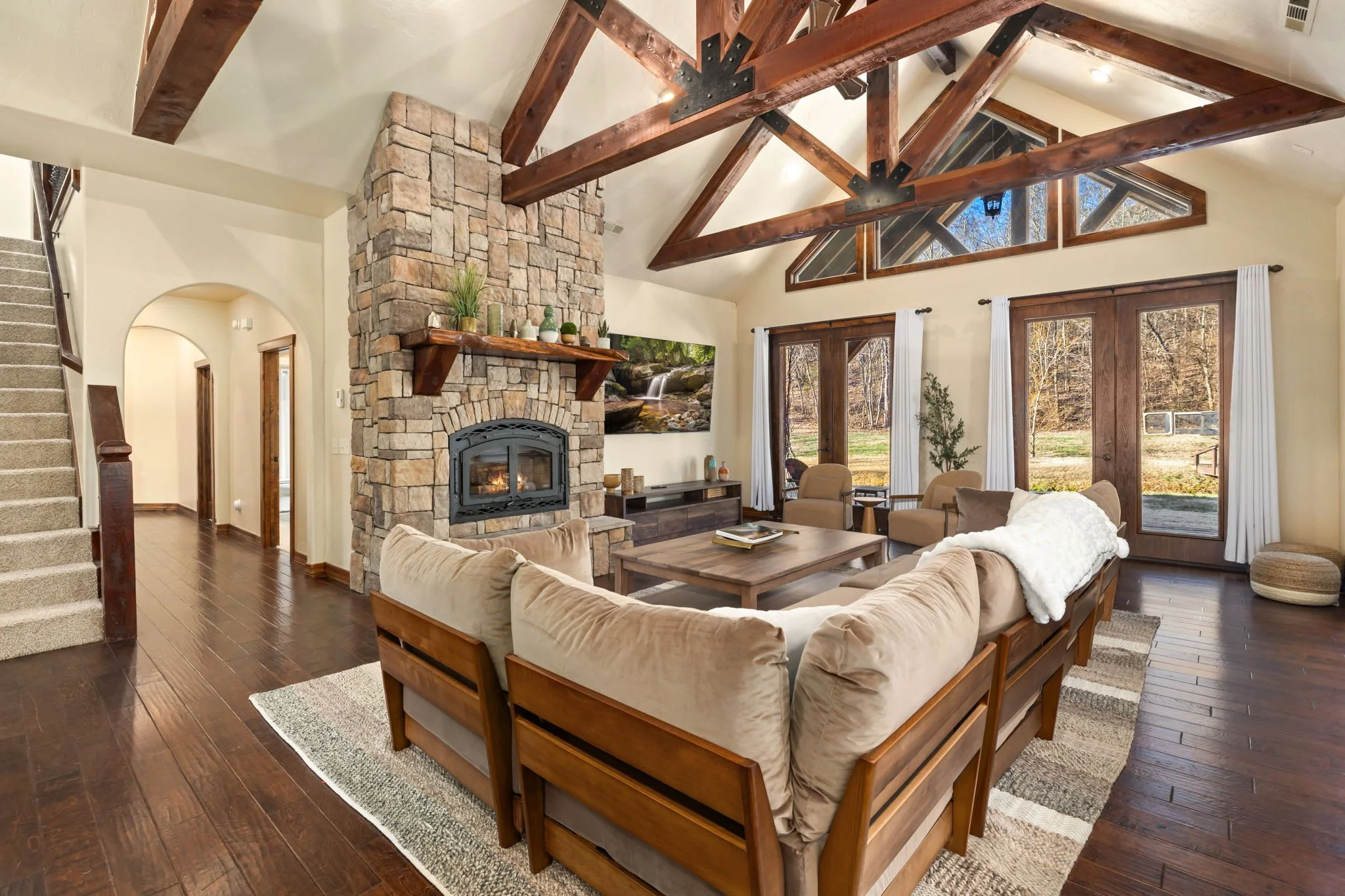 Gorgeous living room with tall ceilings, a stone fireplace, and a large smart TV.