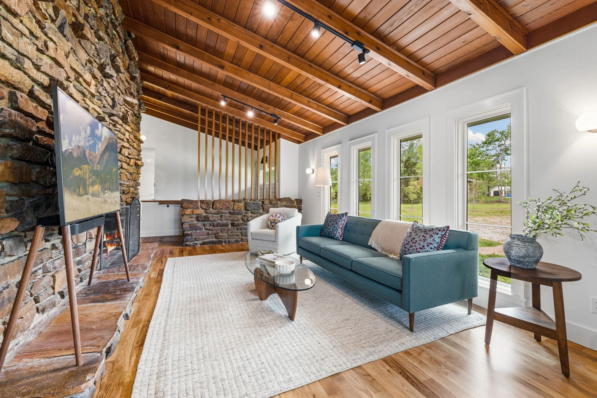 Our main living room is complete with comfy seating, a large Smart TV, Sonos sound system, a stone wall and gas fireplace, and stunning mid-modern decor.