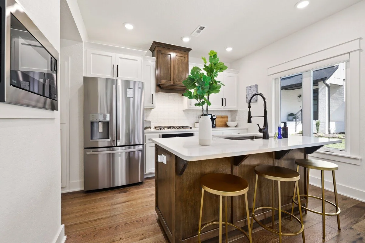  In the center of our kitchen, you'll see our large island, which hosts our sink and three gold barstools.