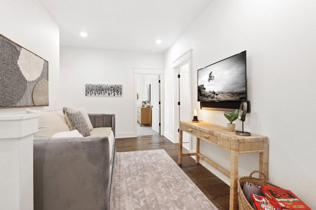 Head upstairs and you'll enter our Bonus Room. Here, you'll find a gray daybed and 43-inch TCL Roku TV.