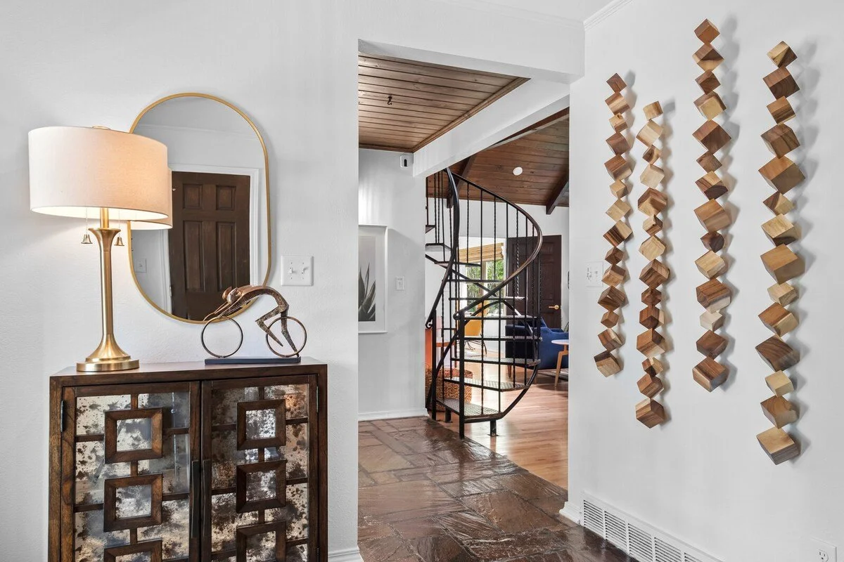 When you walk through our front door, you'll enter into our foyer area. Here, you'll see a credenza, mirror and gorgeous wooden art piece hanging on the wall. Immediately to the left, you'll see our spiral staircase. Immediately ahead, you'll see a d