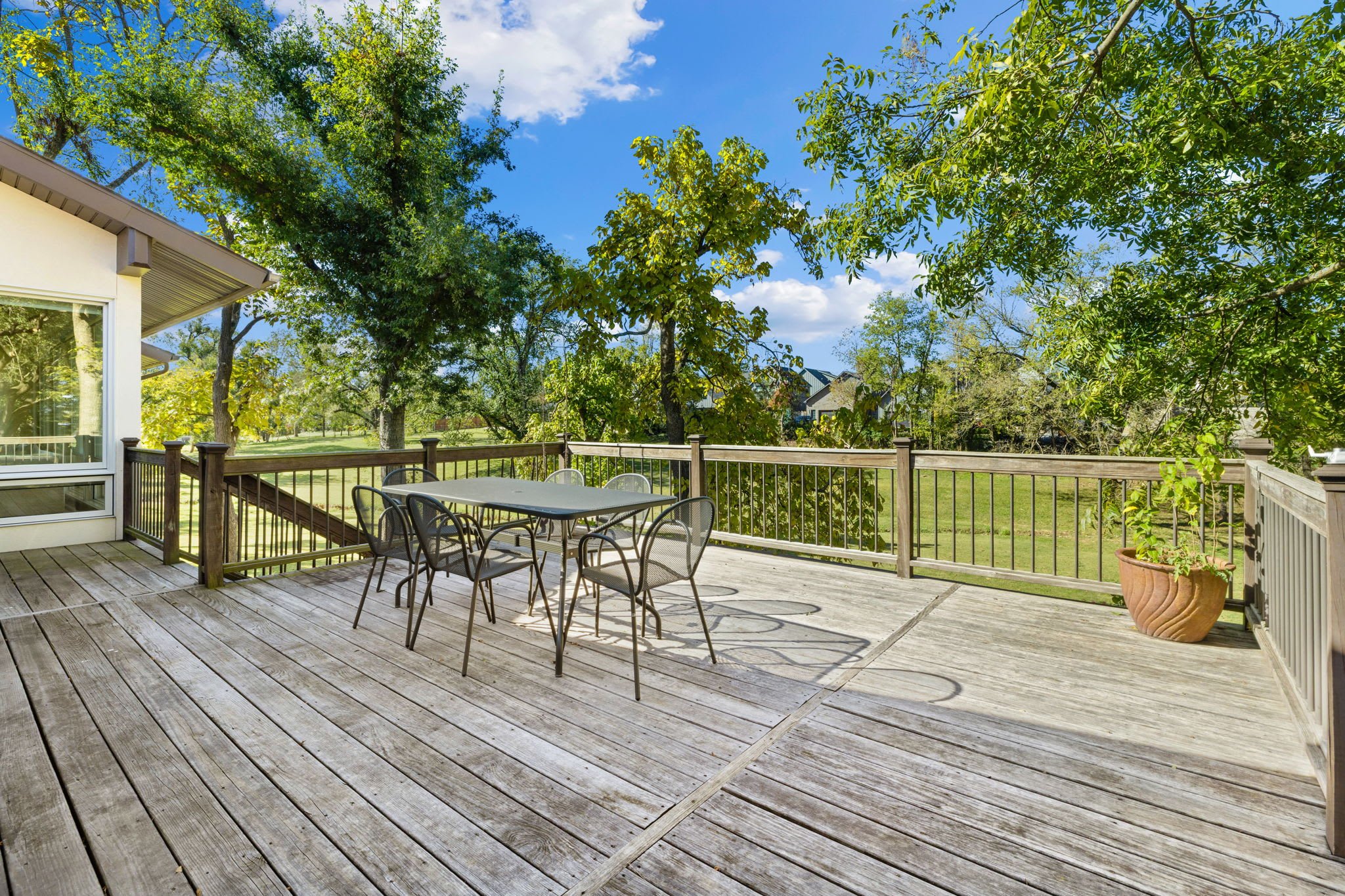 Huge patio deck with outdoor dining table, grill, and view of the open acreage. 