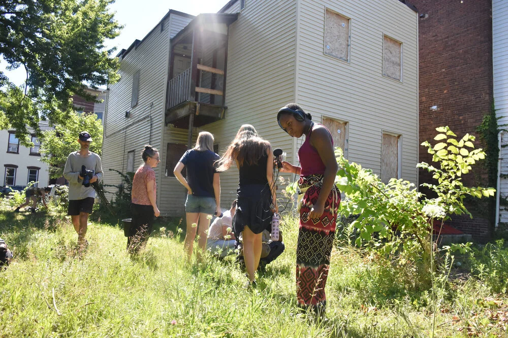  Uptown Summer youth, interns and staff search the area behind an abandoned building for native seeds in North Troy, N.Y. on July 19, 2018. The building is in the process of being transformed by The Sanctuary for Independent Media into a community sc