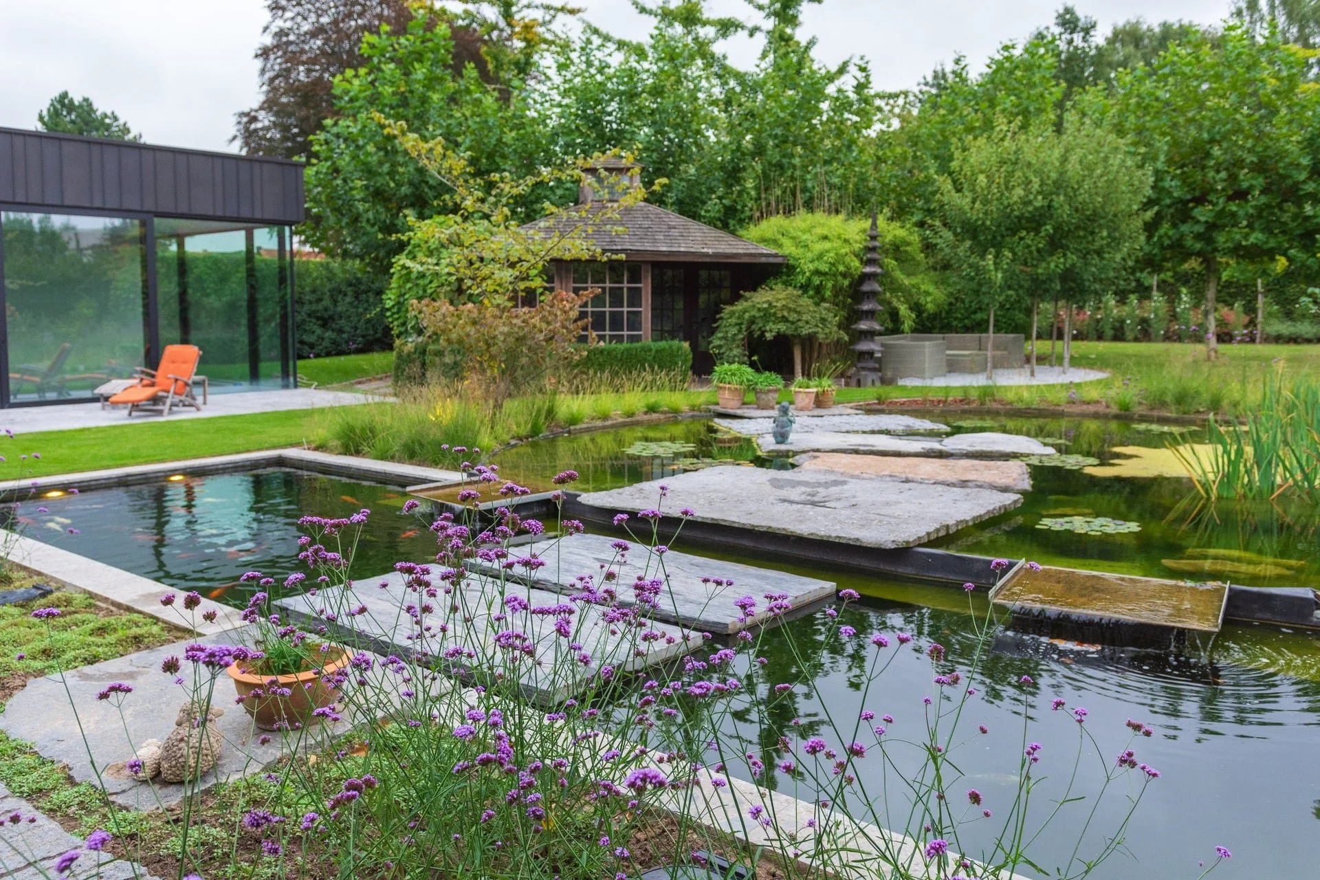 Zwemvijver met houten tuinpaviljoen en rietbeplanting