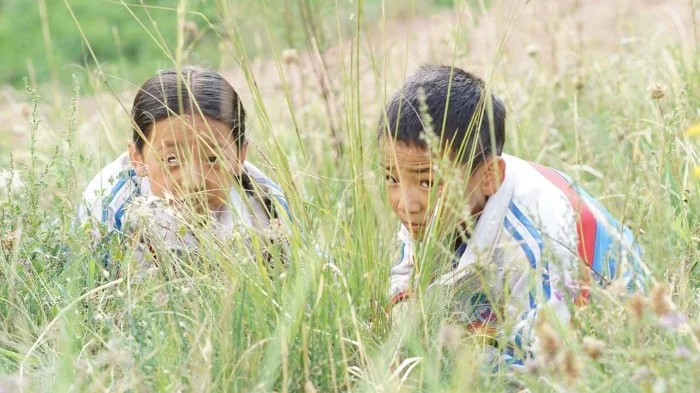 Wangdrak’s Rainboots Lhapa Gyal | 2018 | Tibet | Drama | 90’ | Tibetan with English Subtitles It is the rainy season in the mountains of Tibet. Good for the grain, bad for the little Wangdrak. He is the only pupil in the village school who has no rubber boots and regularly runs the risk of getting his feet wet on the way to school. To make matters worse, he is exposed to the ridicule of the other children. He therefore desires nothing more than to have a pair of rubber boots. But his father has no money to buy him some, and other worries plague him anyway. The silent stubbornness with which Wangdrak pursues his goal determines the further course of the story. The film, based on a novel by Tserang Dondrup, gives attention to the boy’s feelings in a lovingly attentive way and tells the story entirely from his point of view. Only towards the end does the horizon widen as Wangdrak begins to take an interest in the adult world. He becomes a witness of how their thinking and feeling are directed to the forces of nature.In order to escape the devastation of thunderstorms at harvest time, they leave they are completely devoted to religious ceremonies. The film tells in a quiet and aesthetic visual language a timeless story from rural Tibet, in which the who is embedded in its traditions and in which the modern civilization has barely left its mark. The director Lhapal Gyal, 29 years old, from Amdo, Tibet, has his film education at the Beijing Film Academy. He has also attended Tharlo, a film by the well-known filmmaker Pema Tseden, as executive director of the Director was involved. Wangdrak’s Rain Boots is his first feature film and had its premiere at the Berlinale 2018.