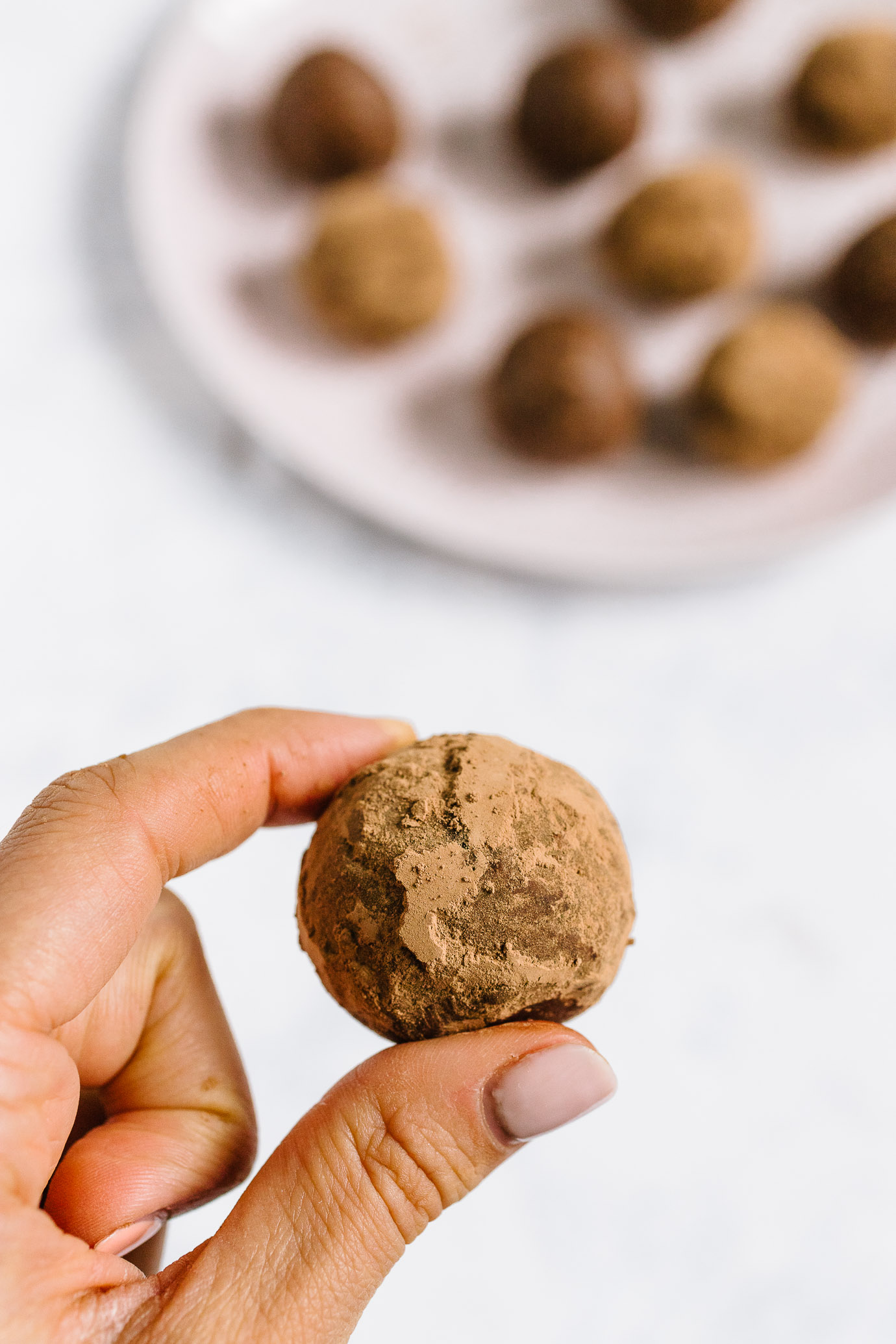 cacao tahini snack bite held between two fingers