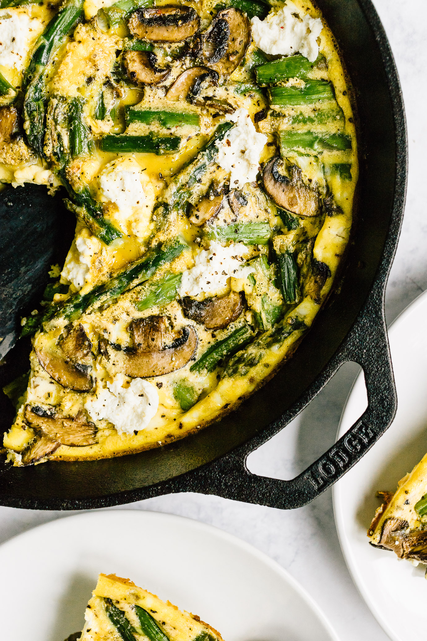 Slice of asparagus mushroom frittata and cast iron skillet