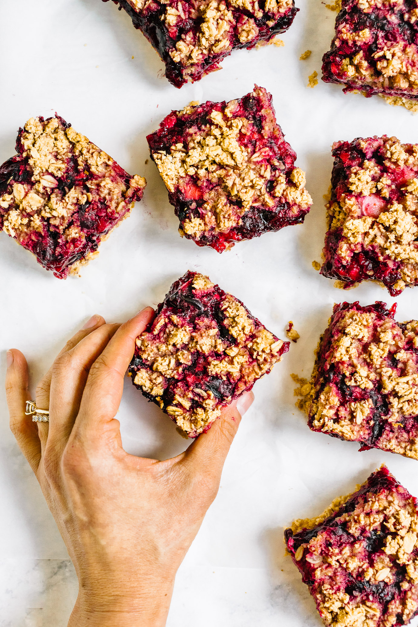 hand picking up sliced mixed berry crumble bar 