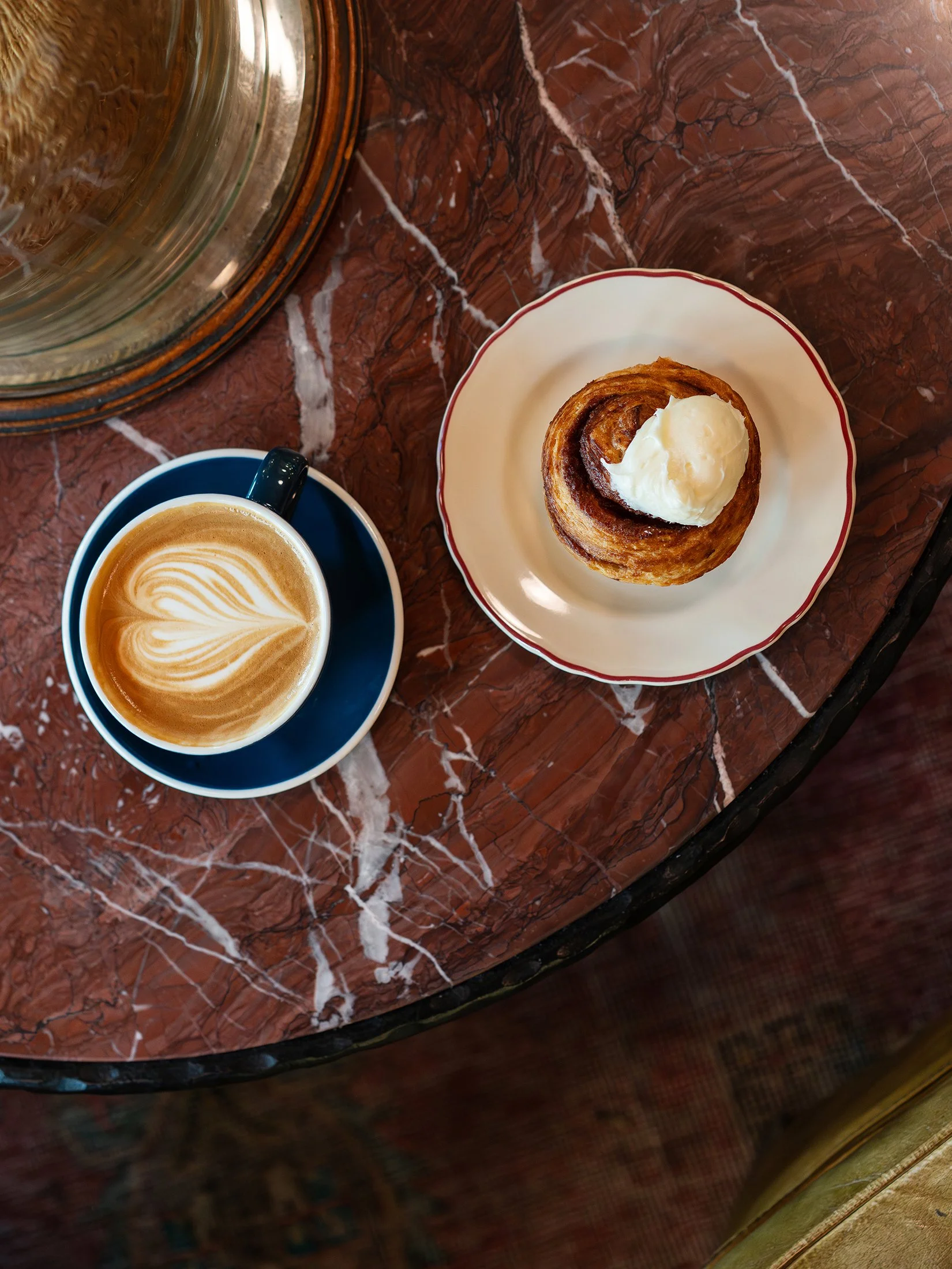 overhead view of marble table with latte and cinnamon roll