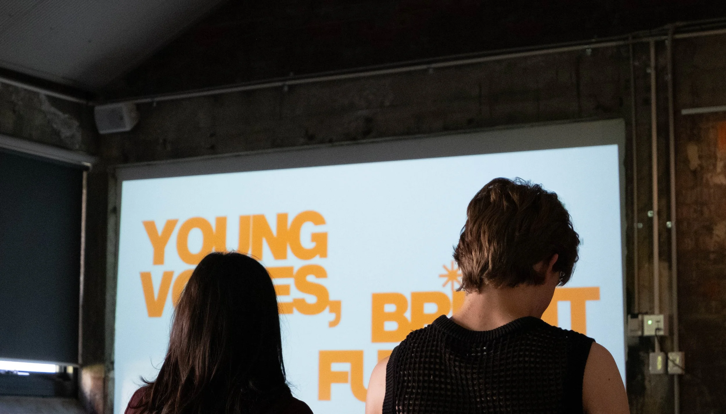 Young Voices, Bright Futures logo is visible on projector screen past the heads of two young people