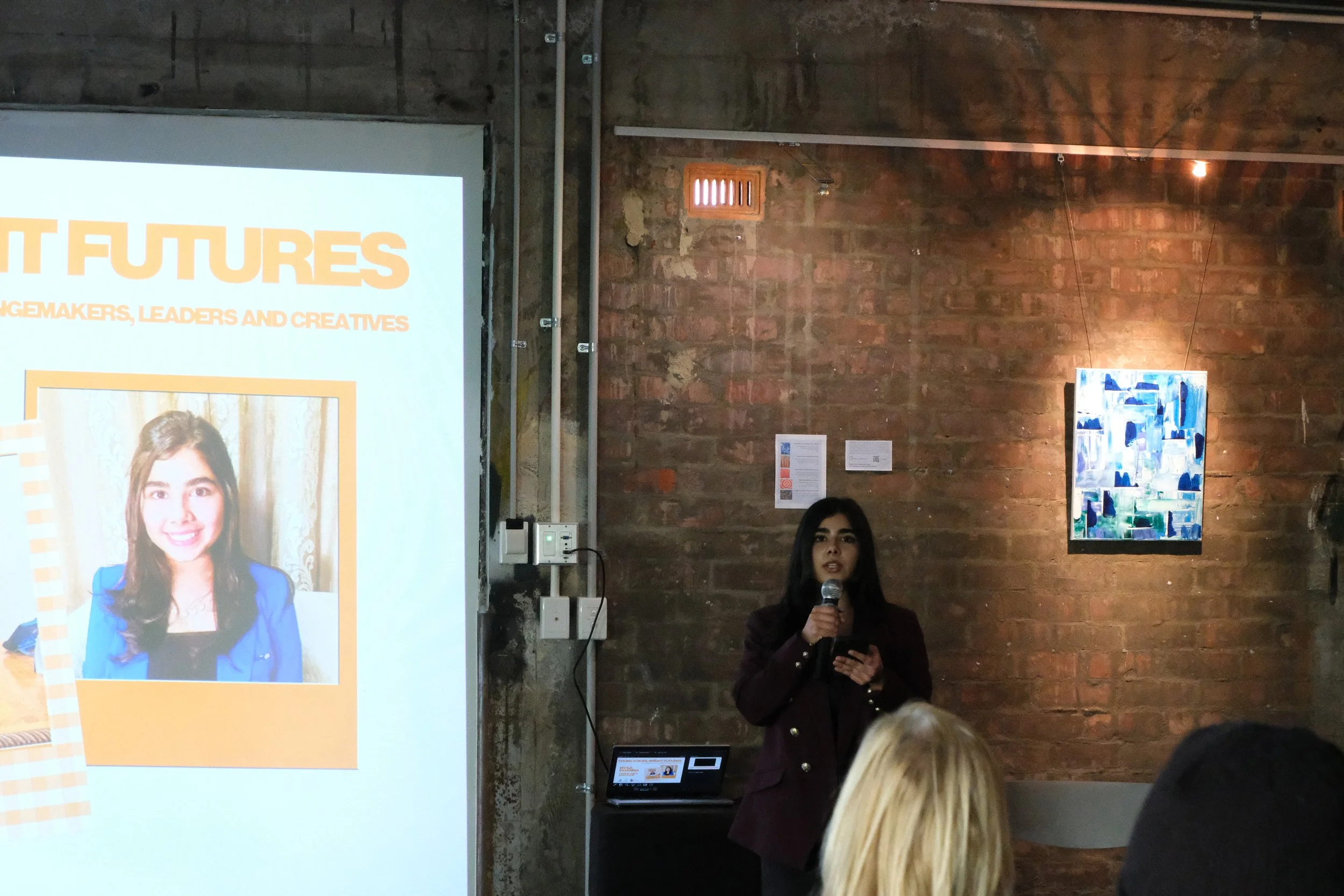 Nysa speaks to audience in front of projector screen