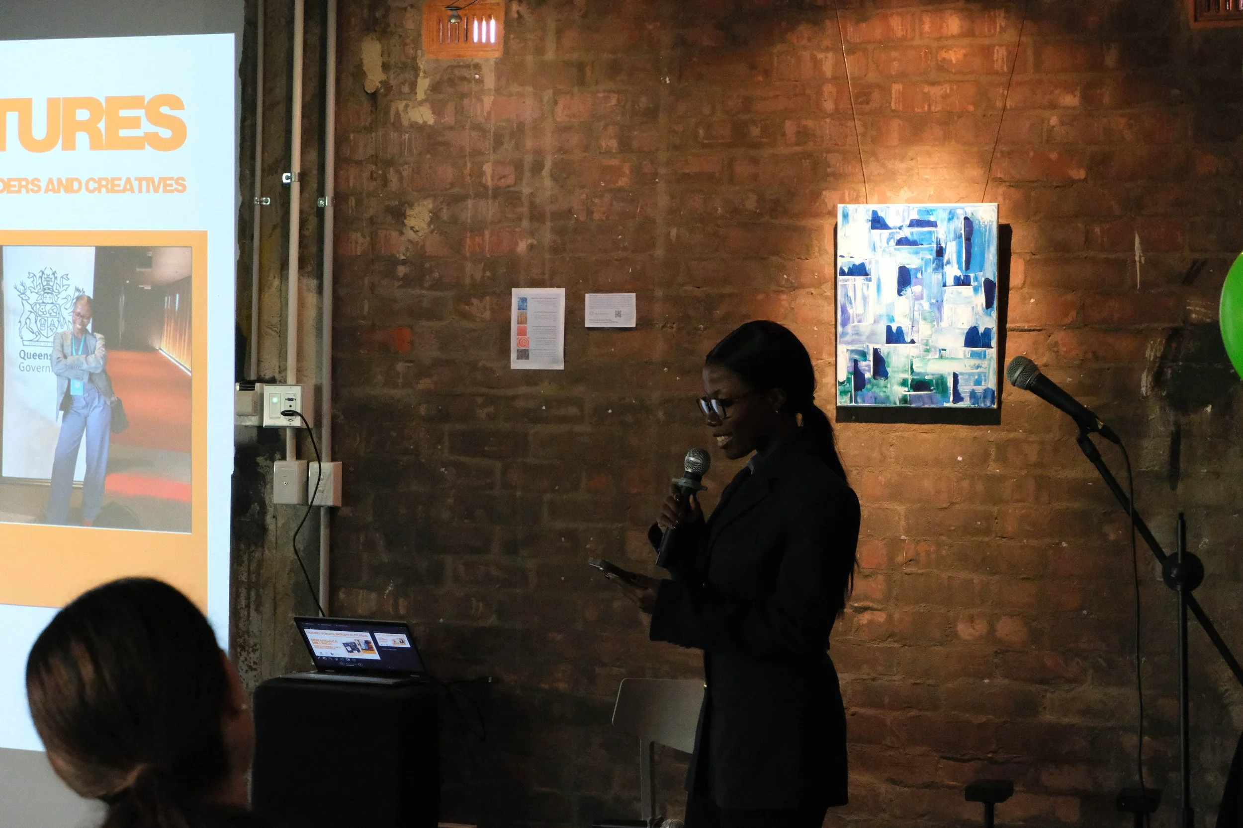 Mwangaza speaks to audience in front of projector screen