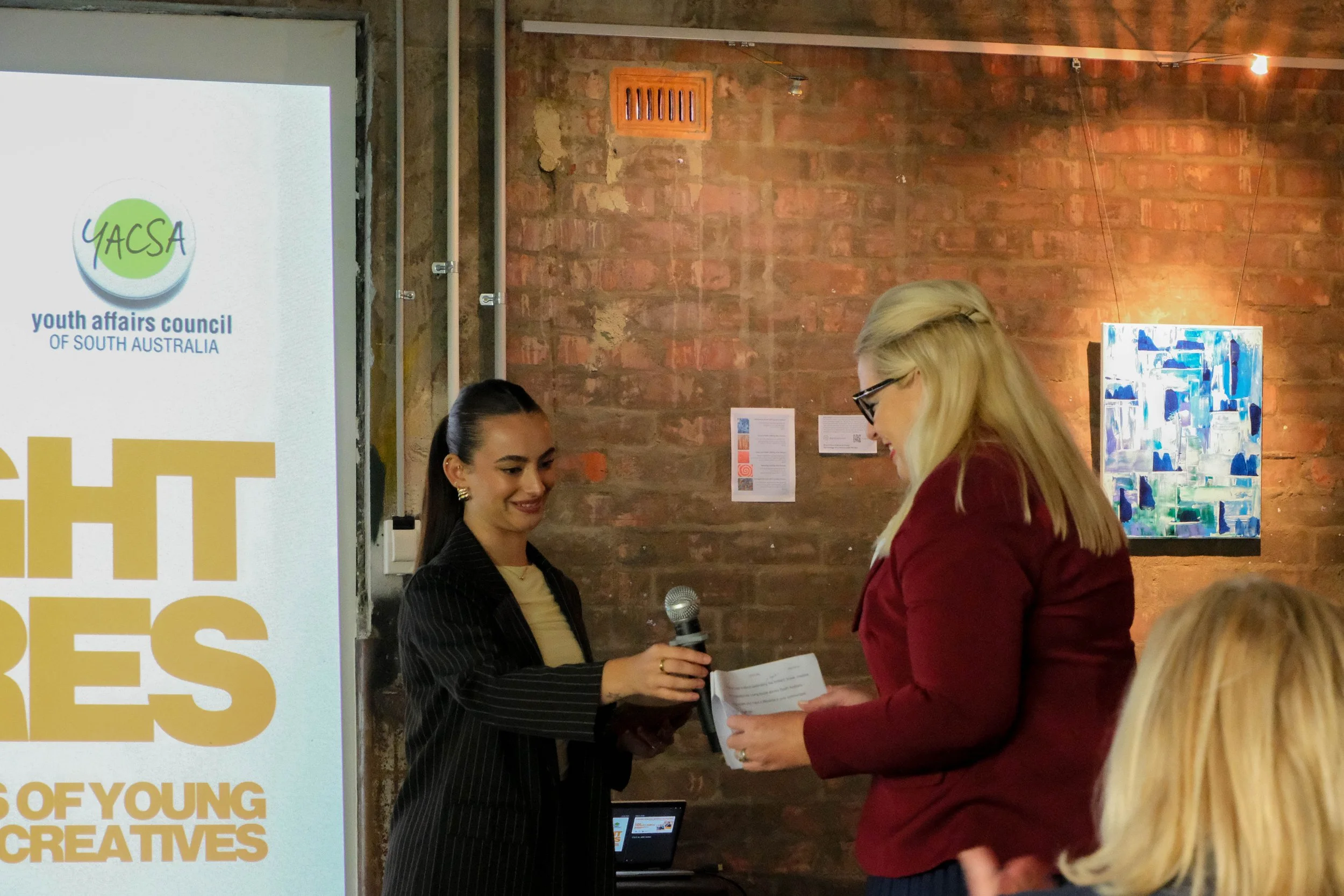 MC, Jess hands microphone to Minister for Human Services Hon Katrine Hildyard MP