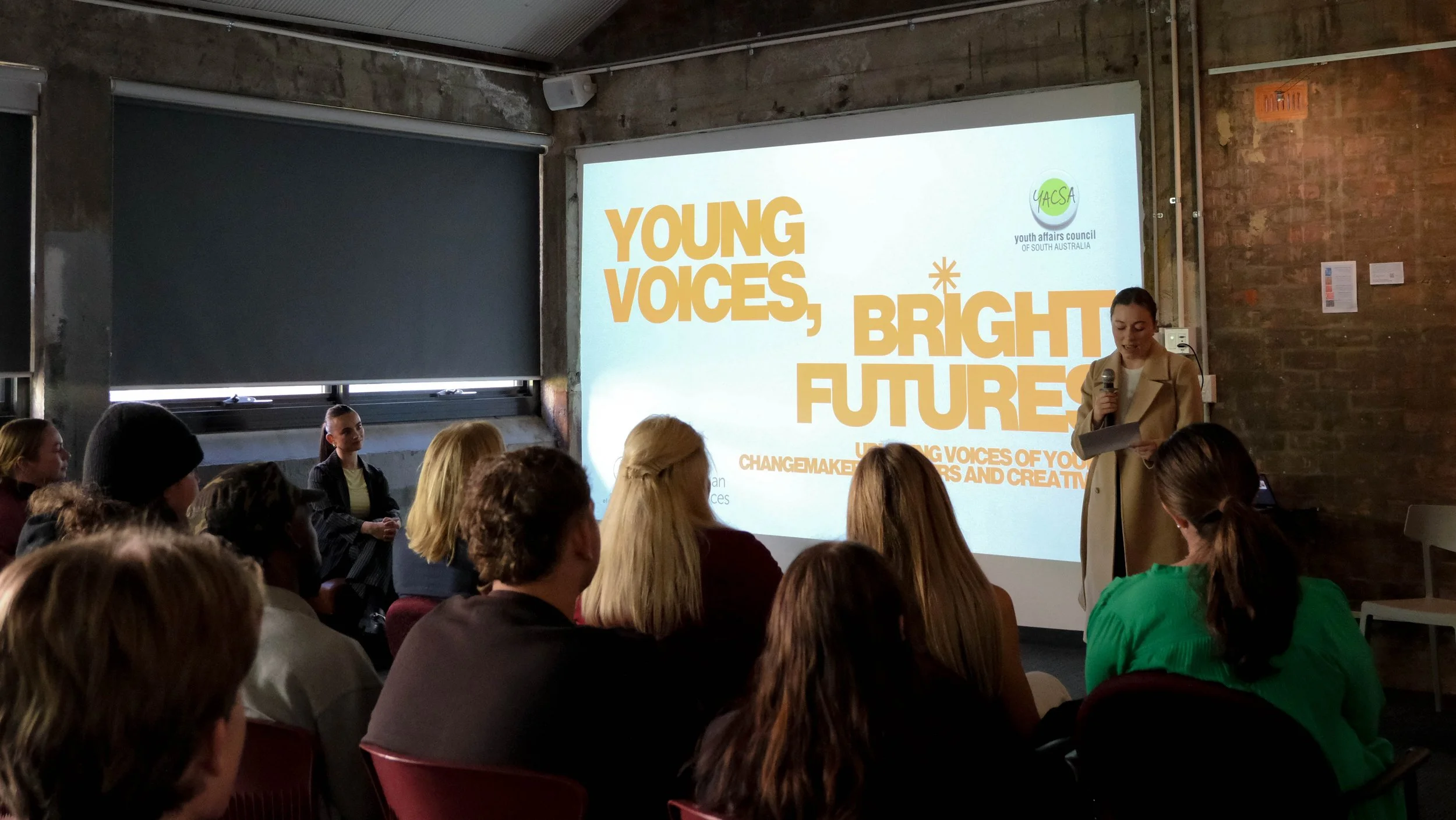 Senator Charlotte Walker speaks to audience in front of projector screen