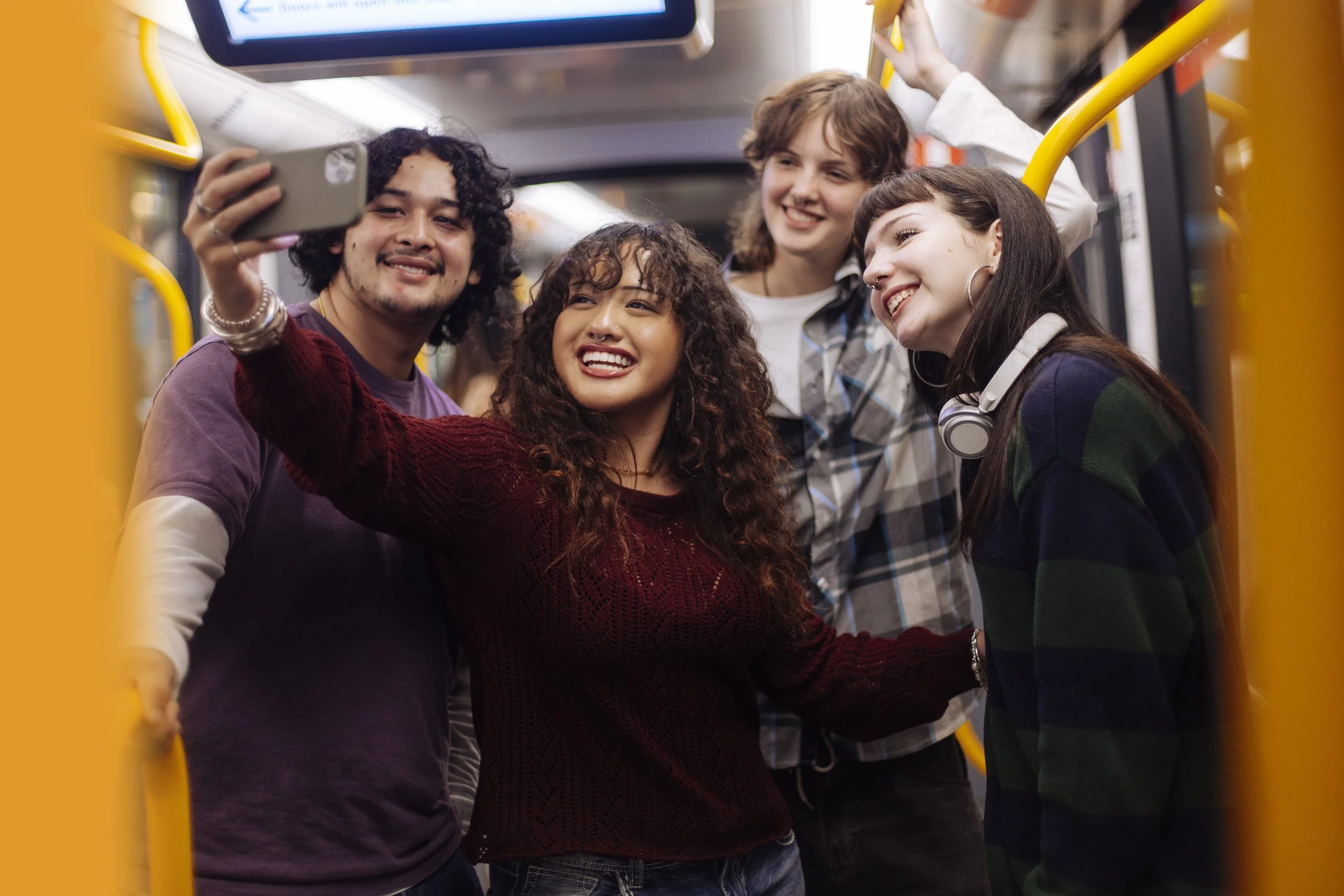 Four teenagers taking a selfie on a tram