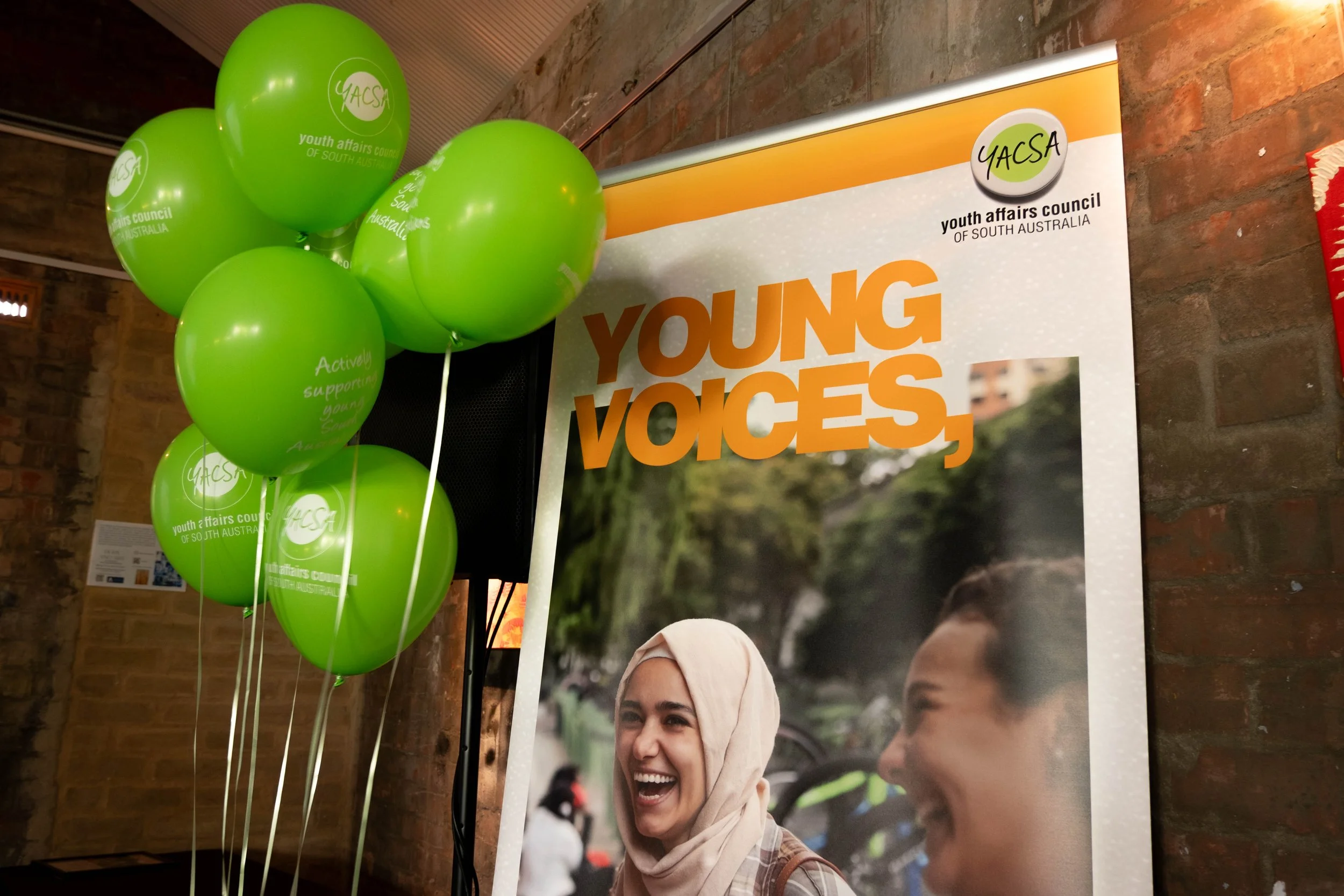 Young Voices, Bright Futures banner and green helium balloons