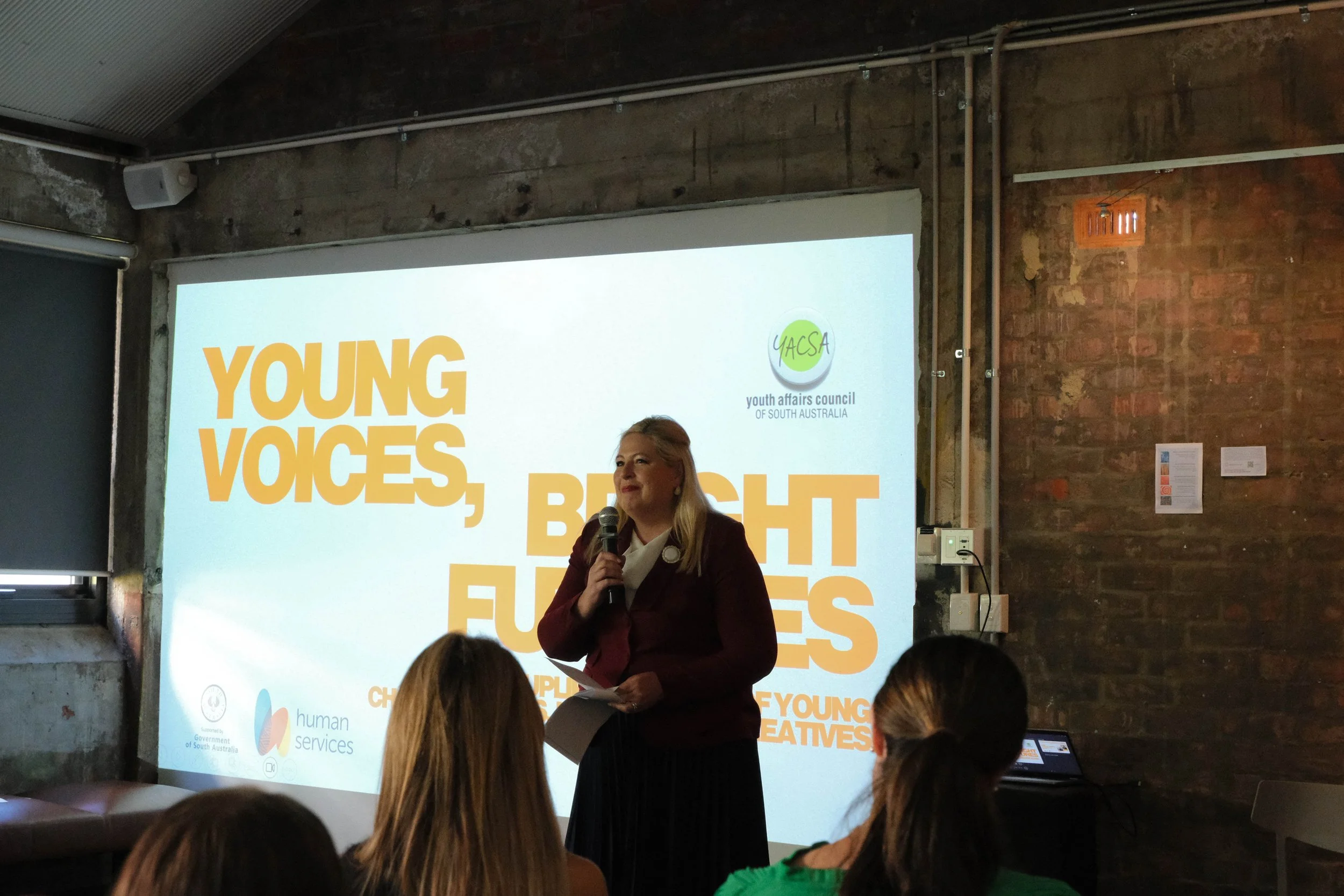 Hon Katrine Hildyard MP speaks to audience in front of projector screen