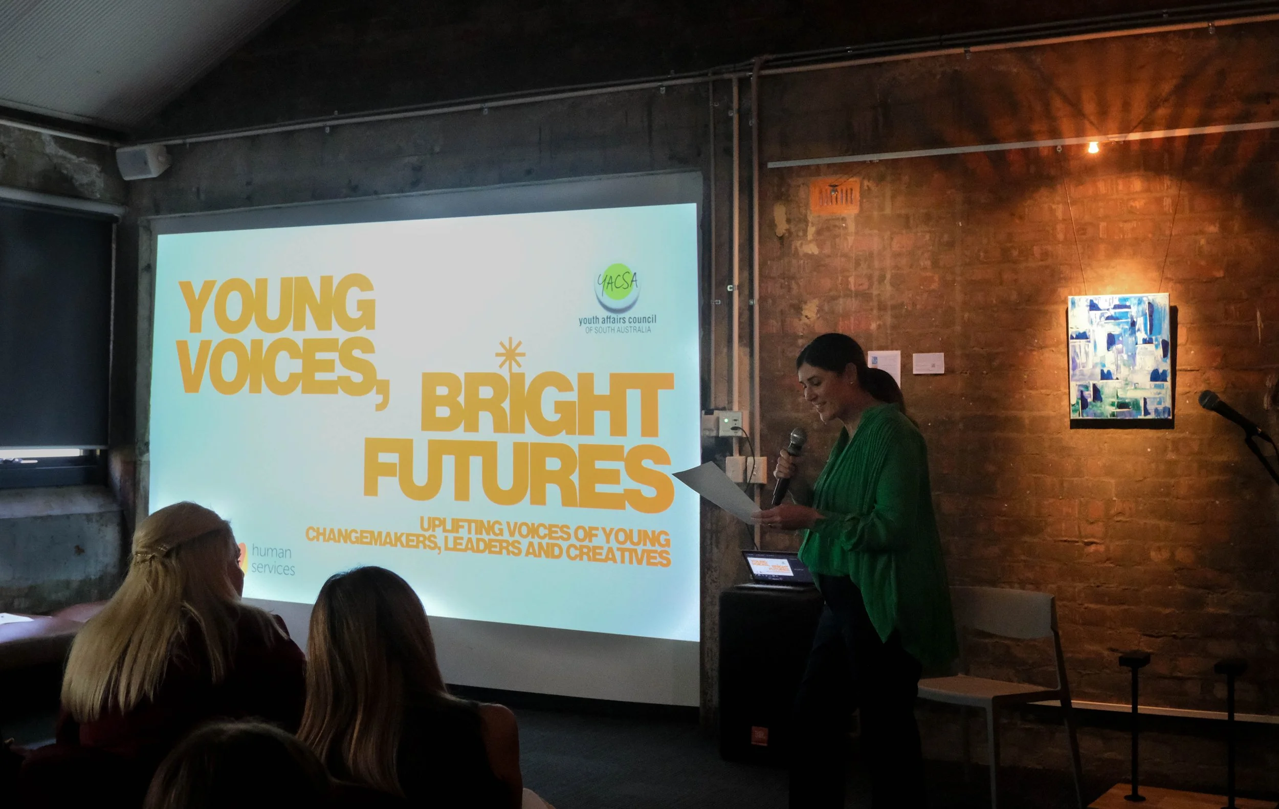 YACSA CEO, Natalie Matulick speaks to audience in front of projector screen
