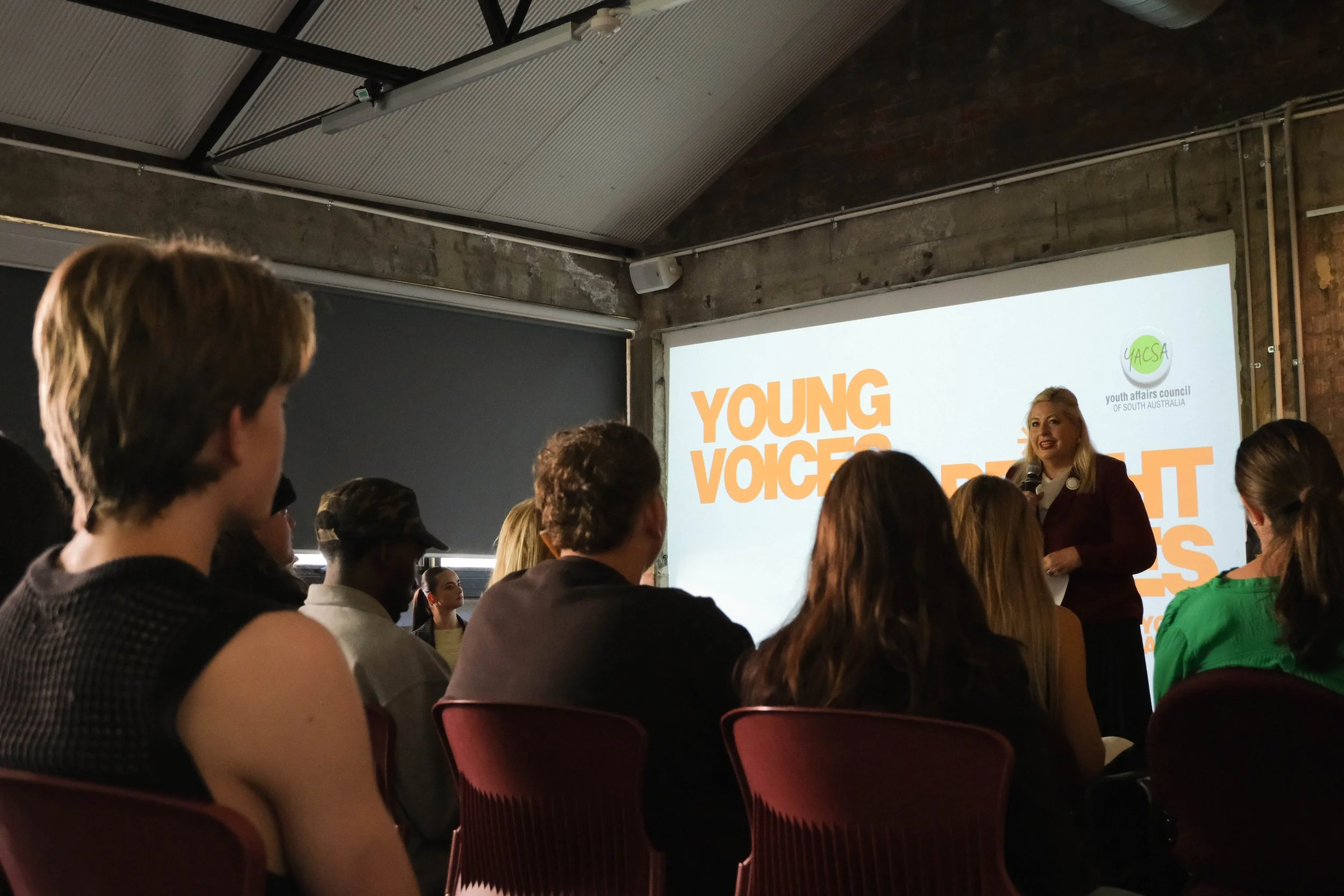 Hon Katrine Hildyard MP speaks to audience in front of projector screen