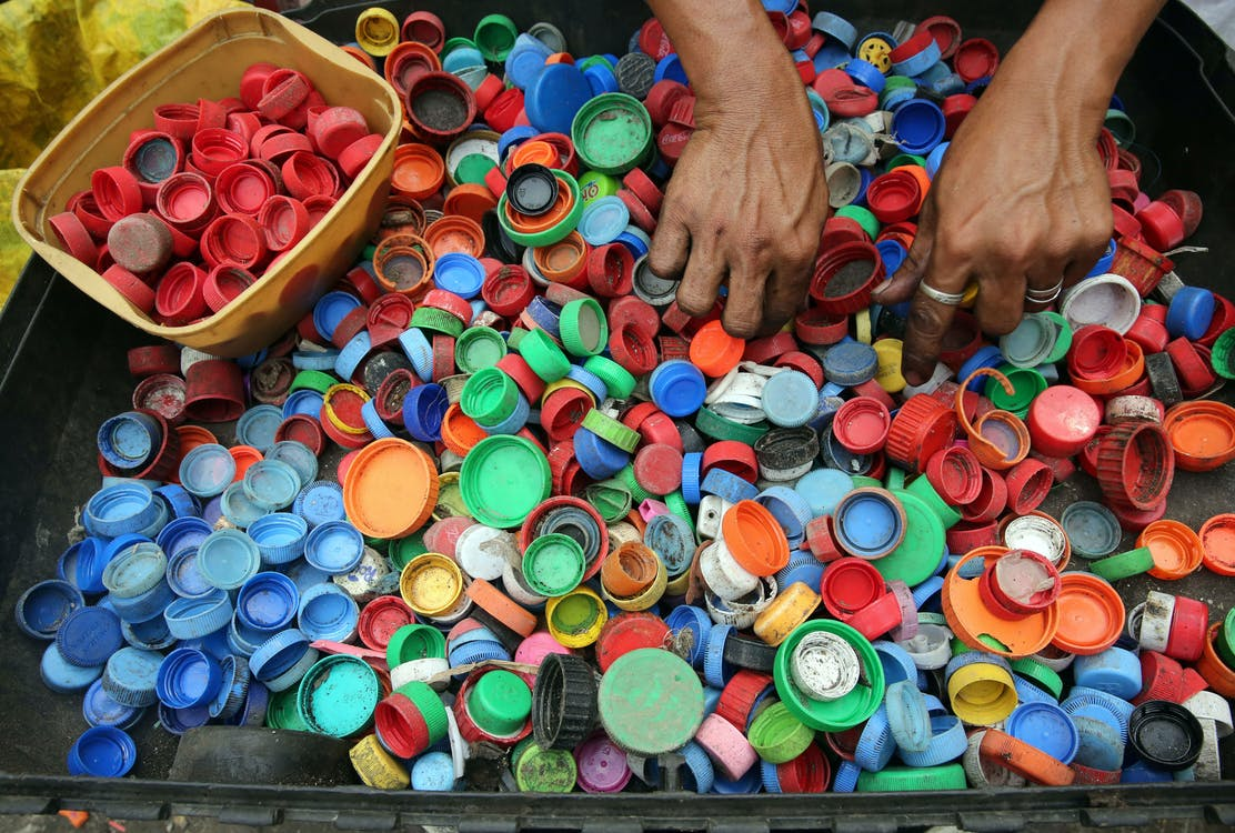 A person recycling bottle caps