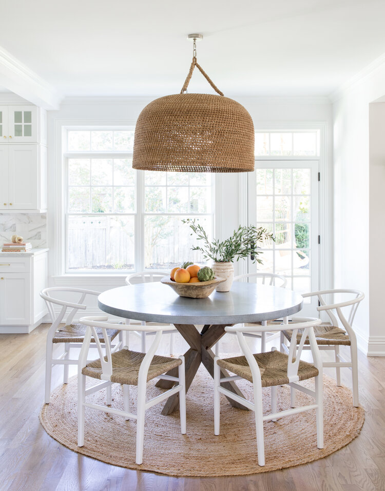 Love the statement woven pendant light, wishbone chairs and round jute rug in this beautiful breakfast nook from Salt Design Co #dining #homedecor #diningroom #kitchennook #breakfastnook #diningnook #nook